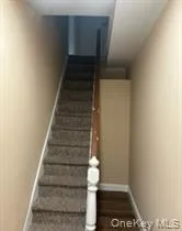 Carpeted staircase with a wood-finish handrail and painted newel post Carpeted staircase with a wood-finish handrail and painted newel post