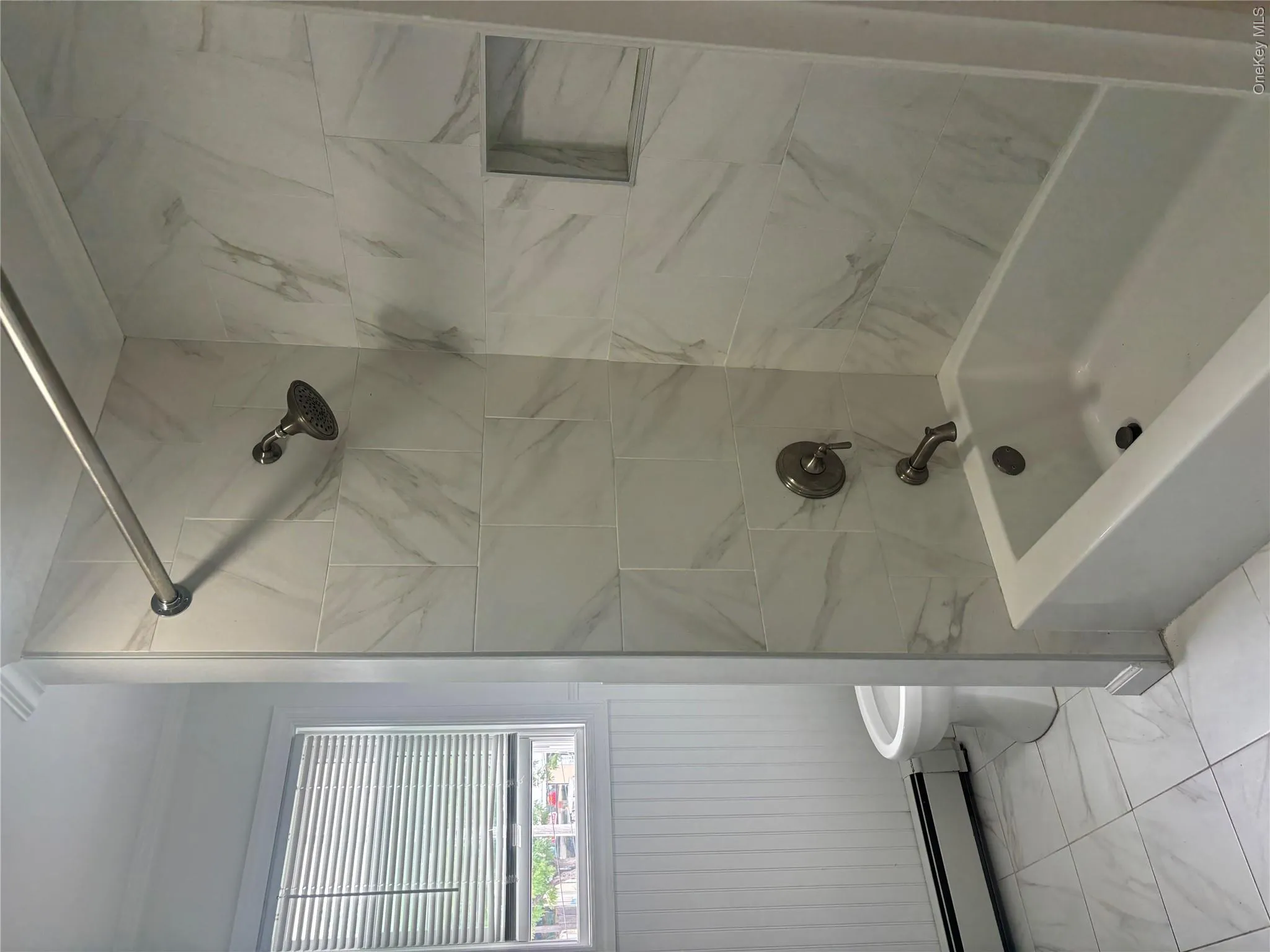 White subway tile shower surround with integrated niche, white bathtub, and brushed nickel fixtures White subway tile shower surround with integrated niche, white bathtub, and brushed nickel fixtures