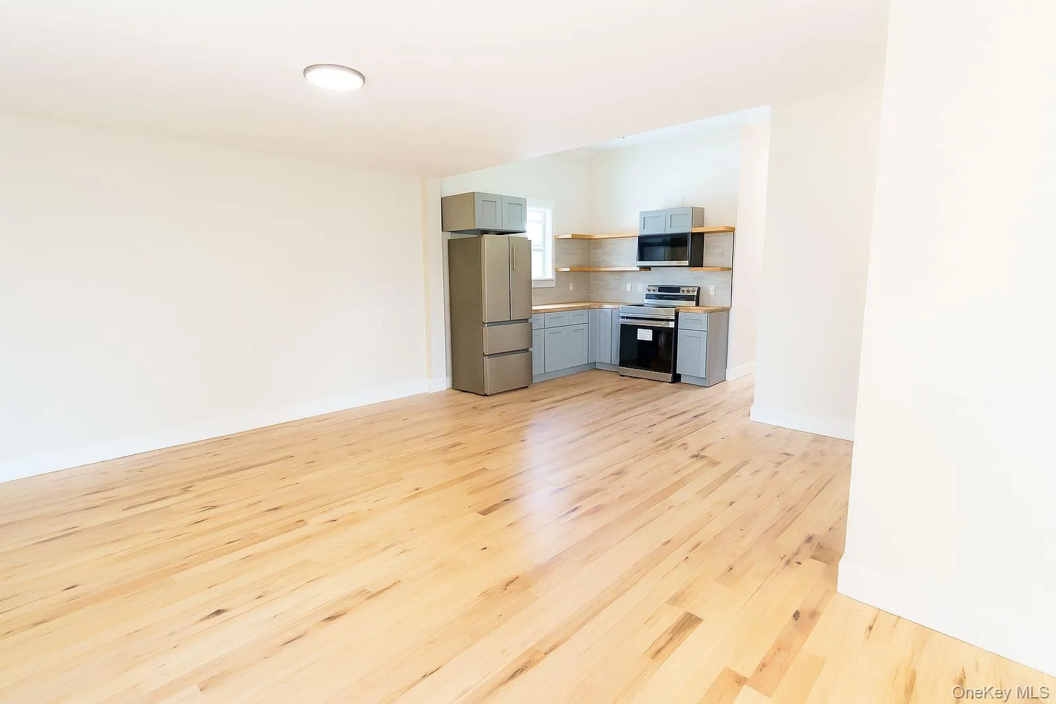 Unfurnished living room featuring light wood-type flooring and baseboards Unfurnished living room featuring light wood-type flooring and baseboards