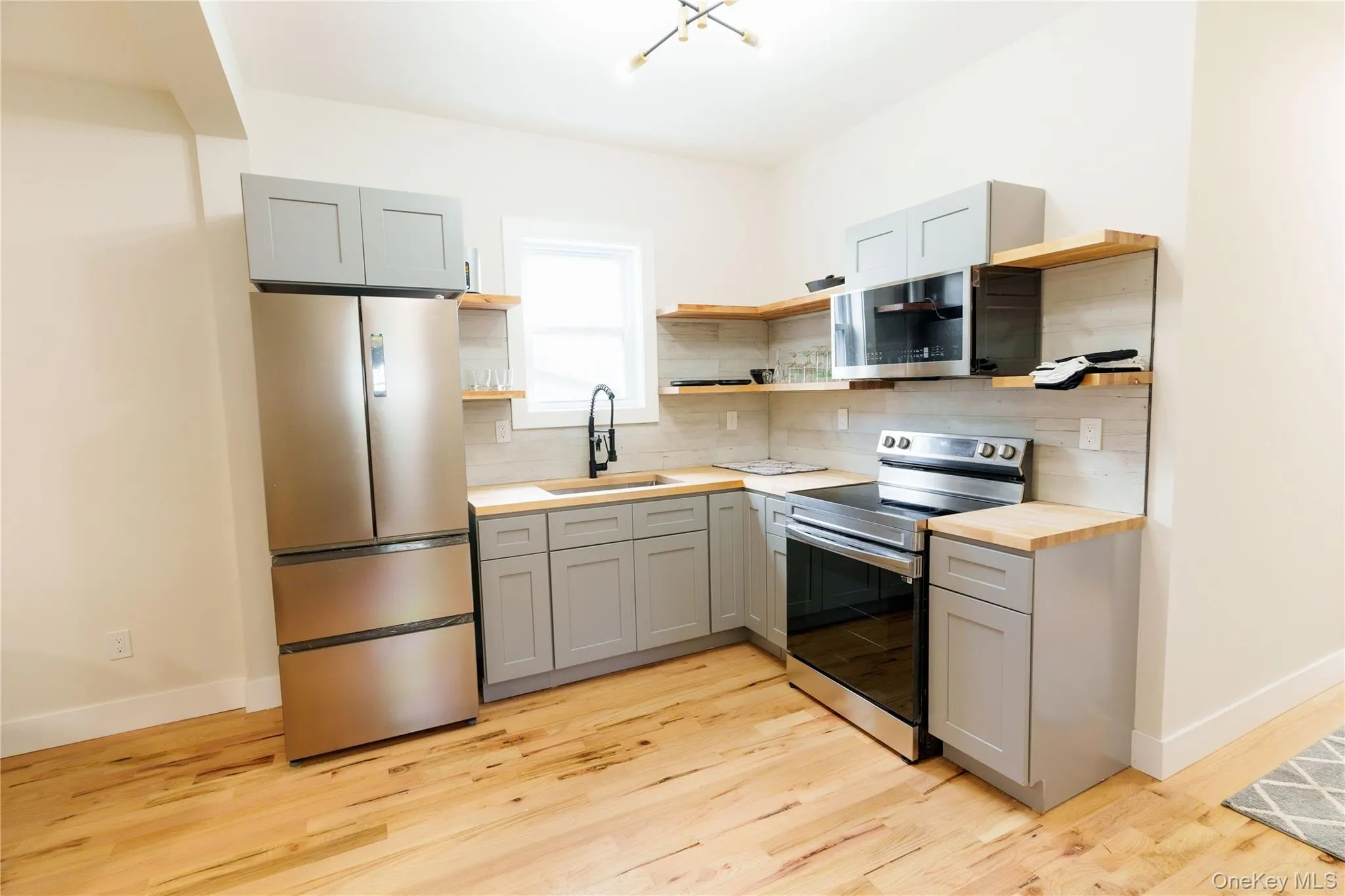 Kitchen with open shelves, gray cabinets, appliances with stainless steel finishes, and wooden counters Kitchen with open shelves, gray cabinets, appliances with stainless steel finishes, and wooden counters