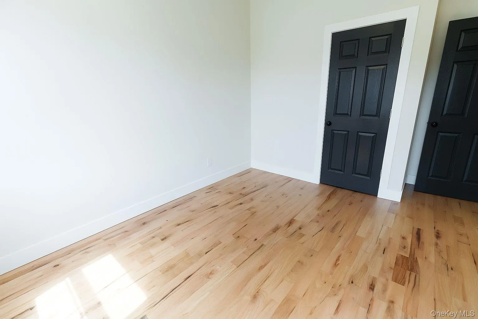 Spare room with baseboards and light wood-style flooring Spare room with baseboards and light wood-style flooring