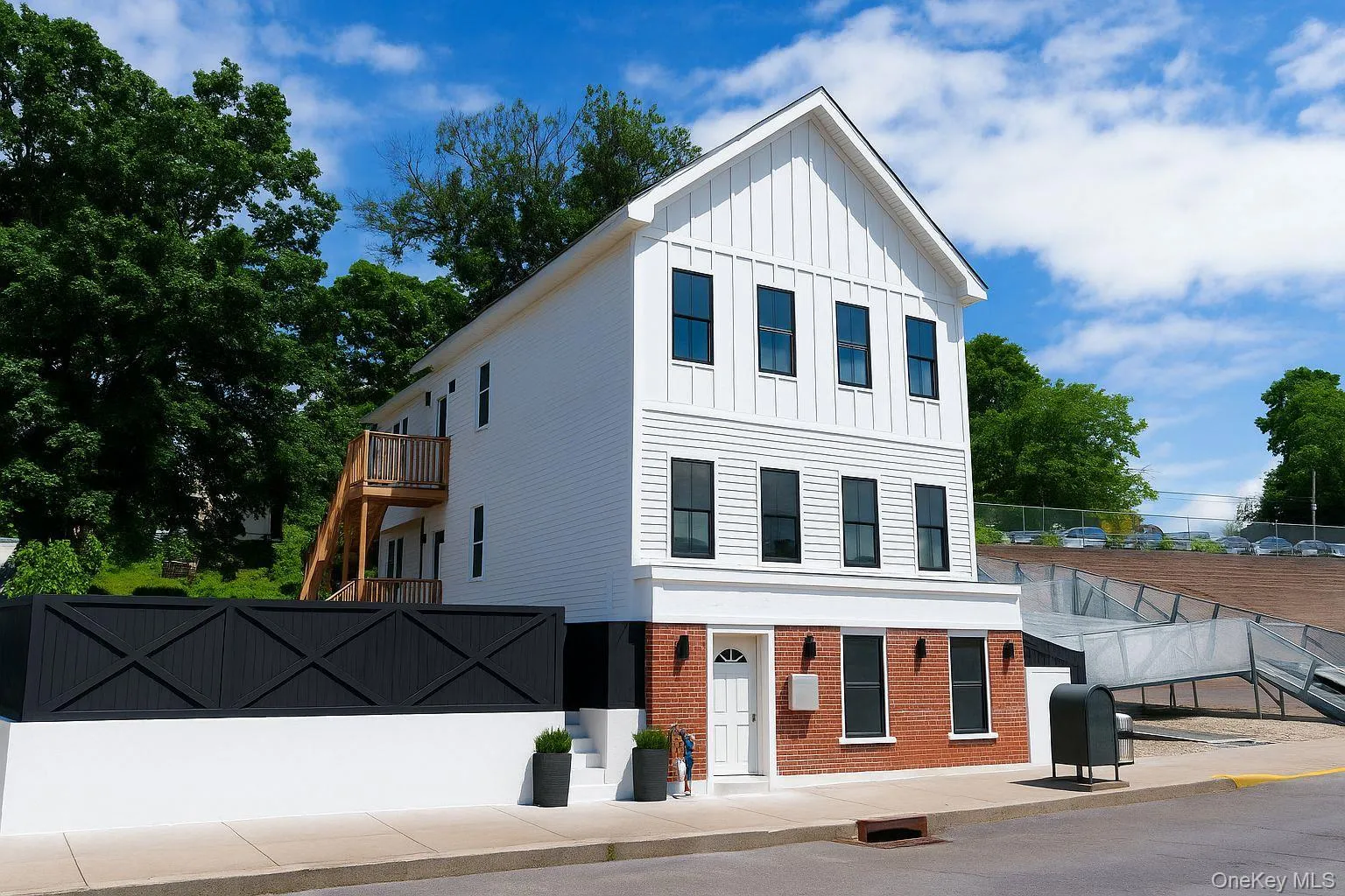 View of front of property featuring board and batten siding, brick siding, a balcony, concrete driveway, and heating fuel View of front of property featuring board and batten siding, brick siding, a balcony, concrete driveway, and heating fuel