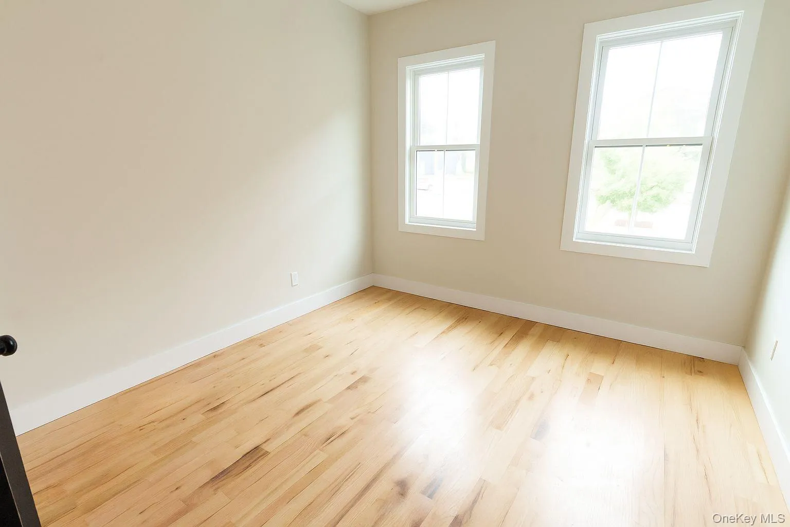 Spare room featuring wood finished floors and baseboards Spare room featuring wood finished floors and baseboards