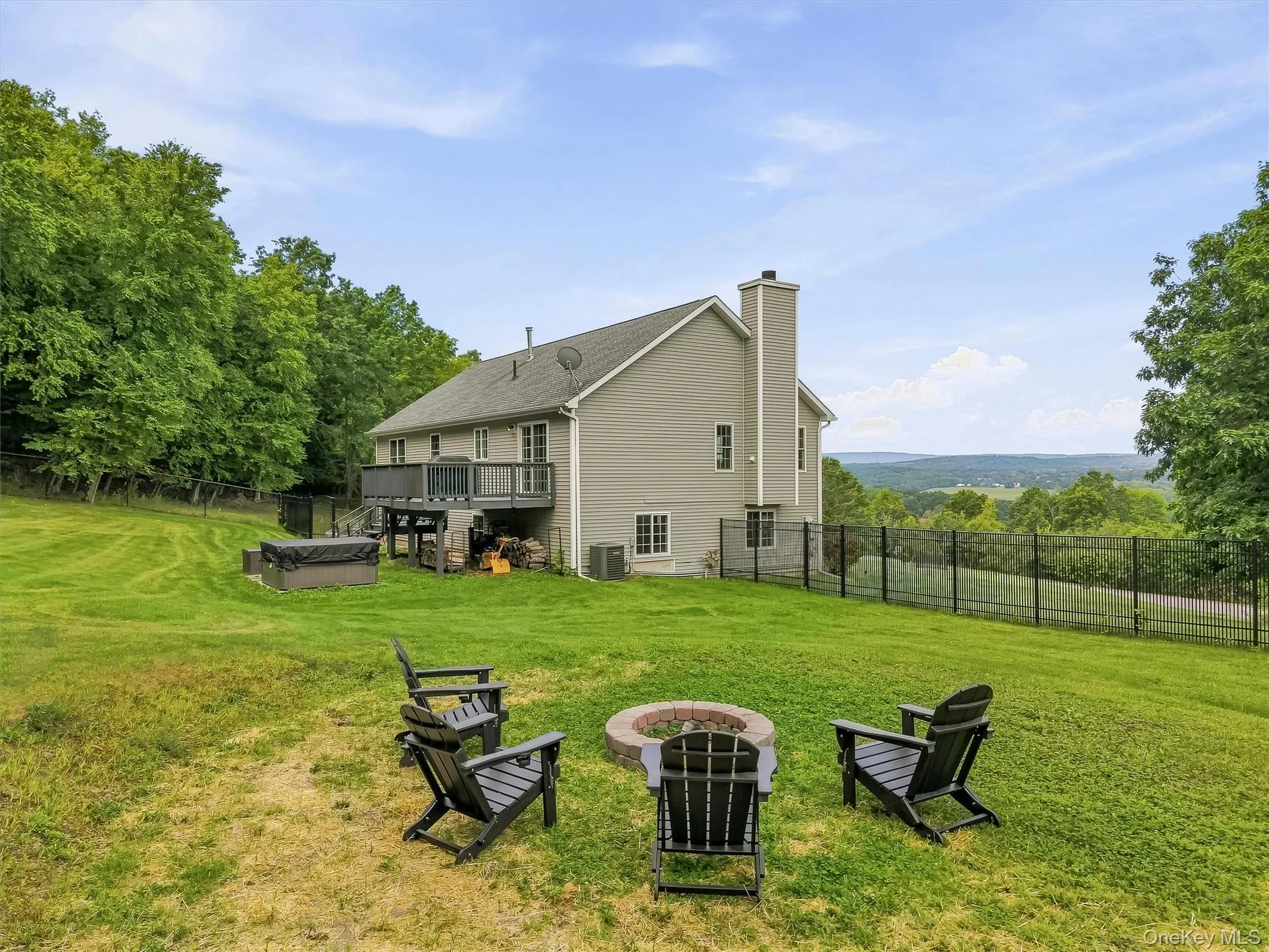Expansive backyard featuring a built-in fire pit, privacy fencing, and an upper-level deck Expansive backyard featuring a built-in fire pit, privacy fencing, and an upper-level deck
