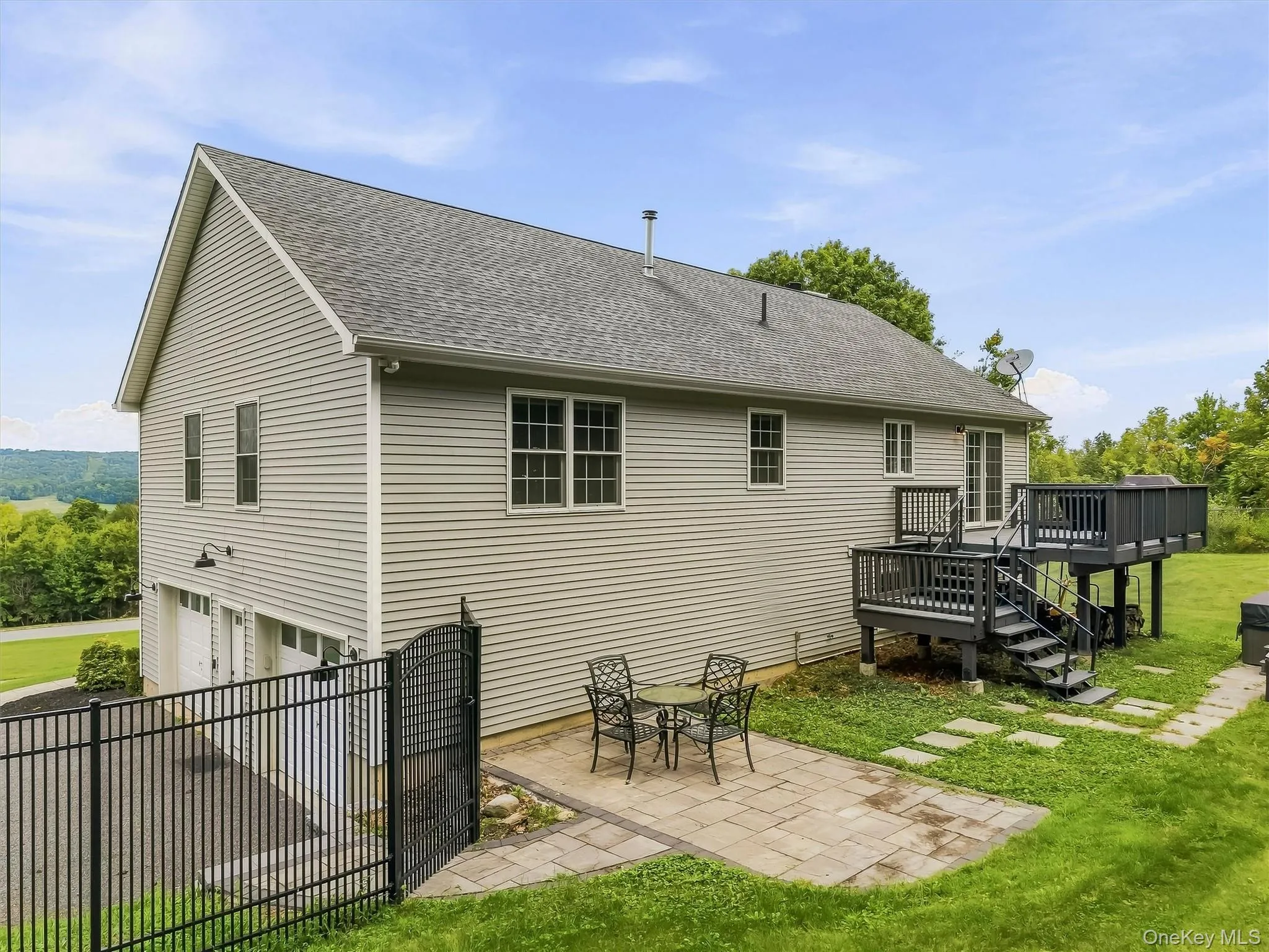 Exterior with gray siding, a multi-level deck, lower patio, and a two-car garage Exterior with gray siding, a multi-level deck, lower patio, and a two-car garage
