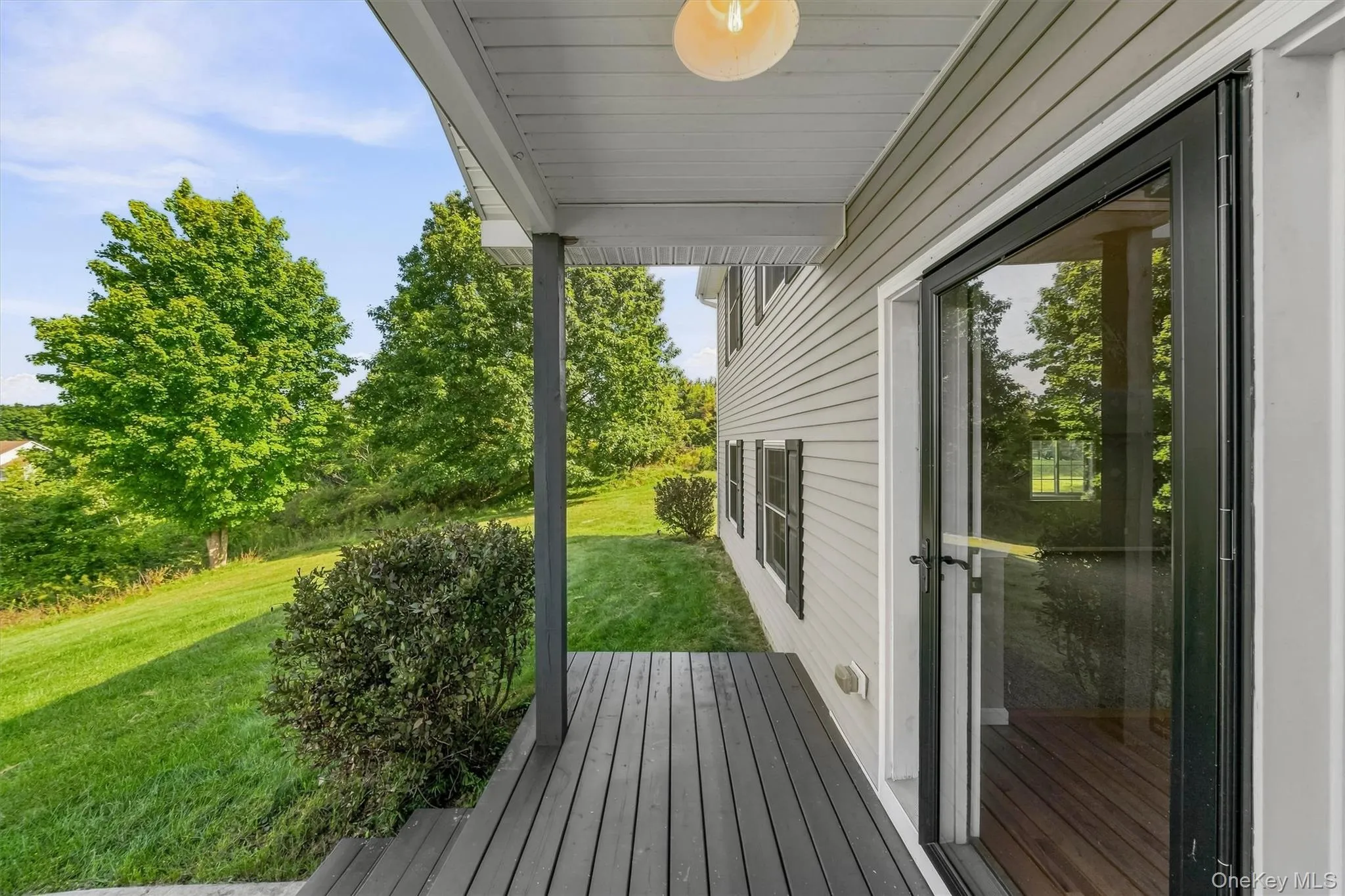 Exterior siding with black shutters, dark wood-finish decking, and a glass-paneled storm door Exterior siding with black shutters, dark wood-finish decking, and a glass-paneled storm door