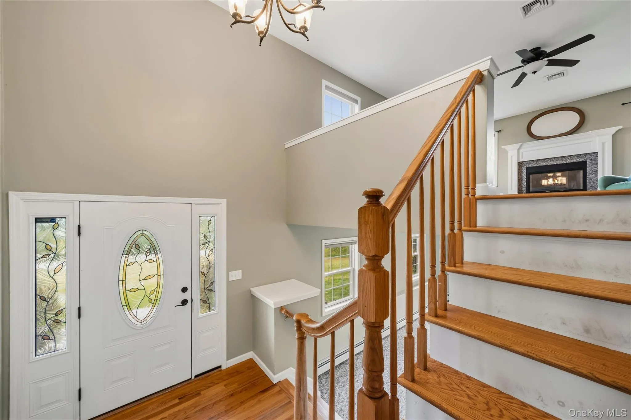 Foyer featuring a decorative glass panel entry door, warm wood-finish flooring, and a chandelier Foyer featuring a decorative glass panel entry door, warm wood-finish flooring, and a chandelier