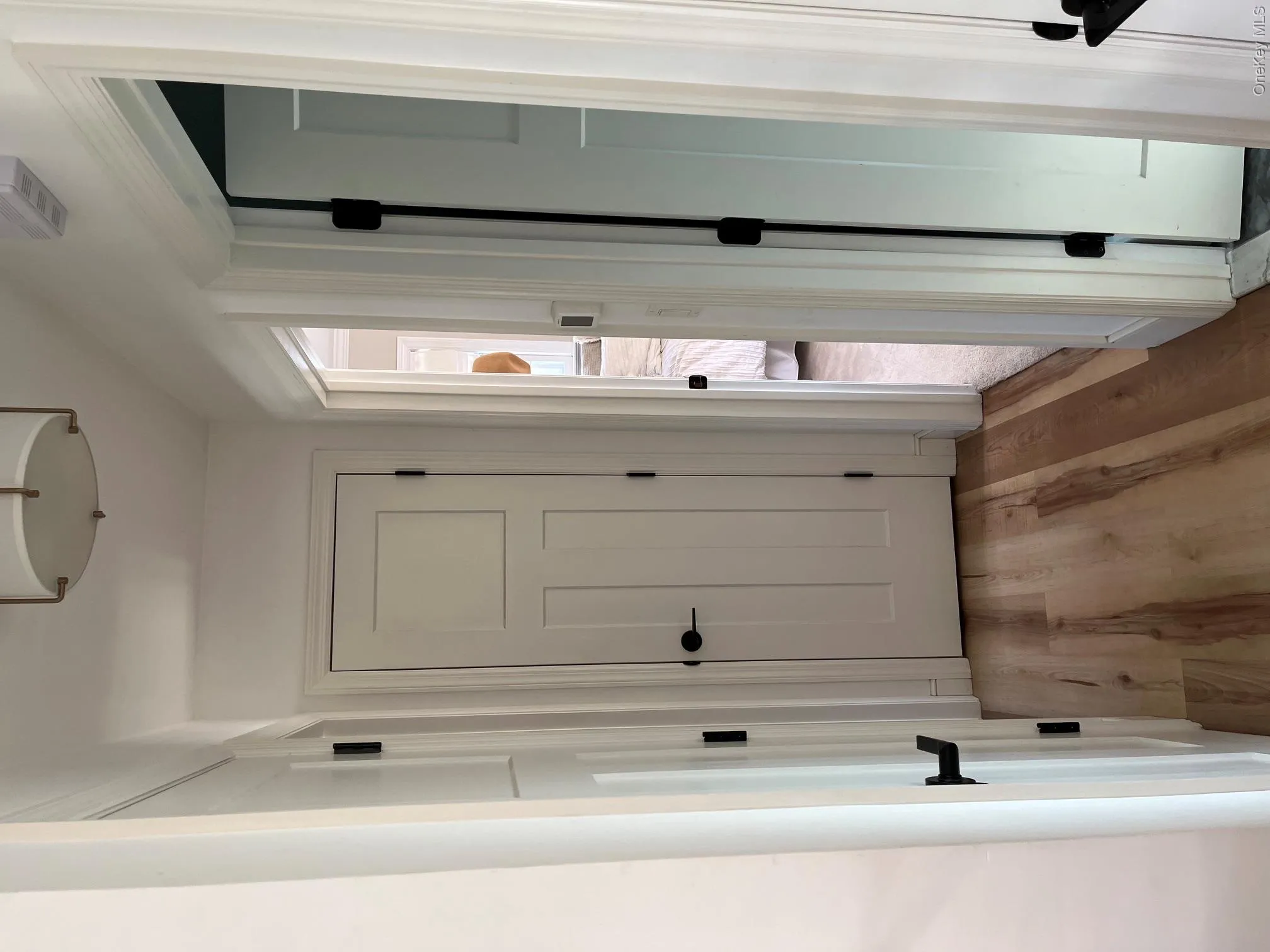 Hallway featuring Luxury Vinyl flooring, white doors with matte black hardware, and a ceiling-mounted light fixture Hallway featuring Luxury Vinyl flooring, white doors with matte black hardware, and a ceiling-mounted light fixture