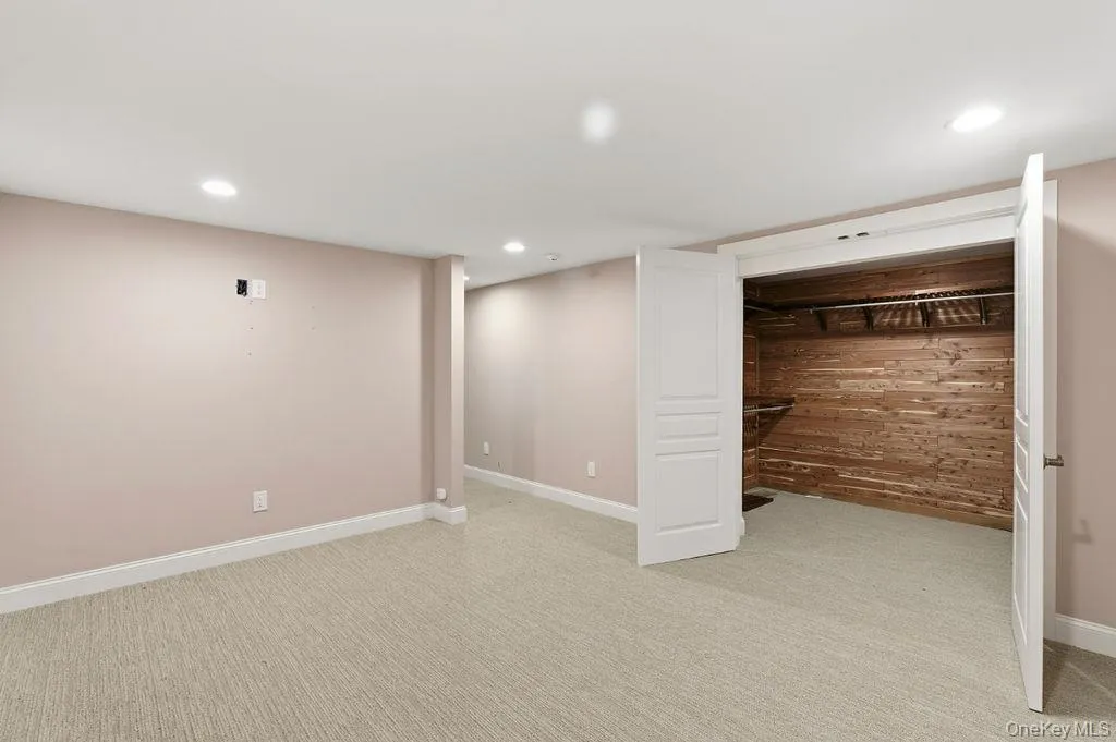 Recessed lighting, light-toned carpeting, wood-paneled closet interior, white trim, and white paneled doors Recessed lighting, light-toned carpeting, wood-paneled closet interior, white trim, and white paneled doors