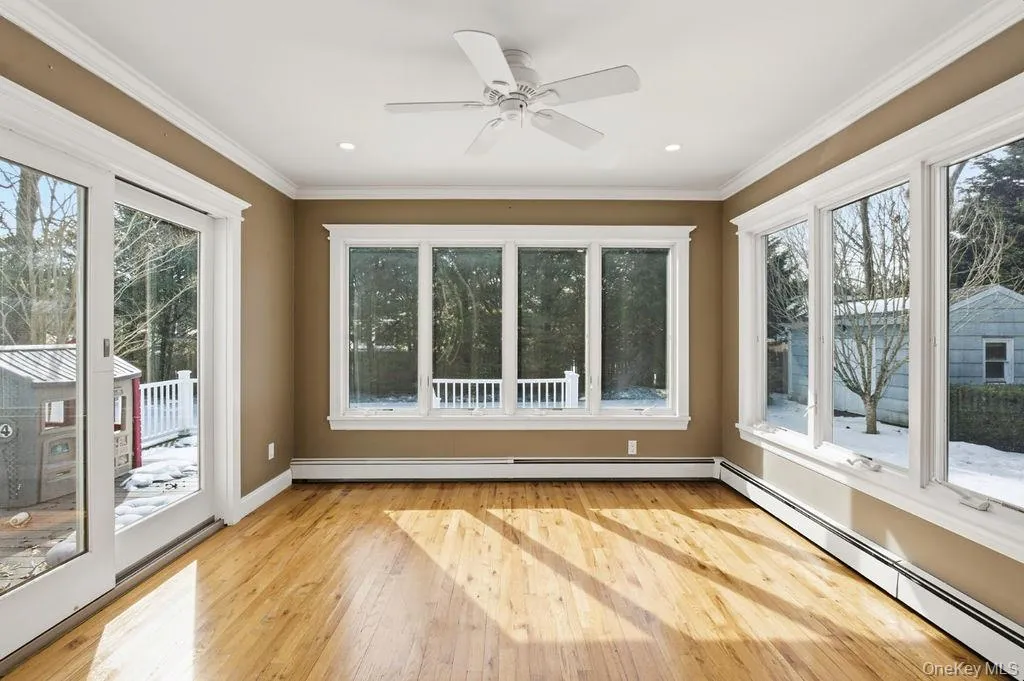 Hardwood flooring, recessed lighting, white ceiling fan, crown molding, and large windows Hardwood flooring, recessed lighting, white ceiling fan, crown molding, and large windows