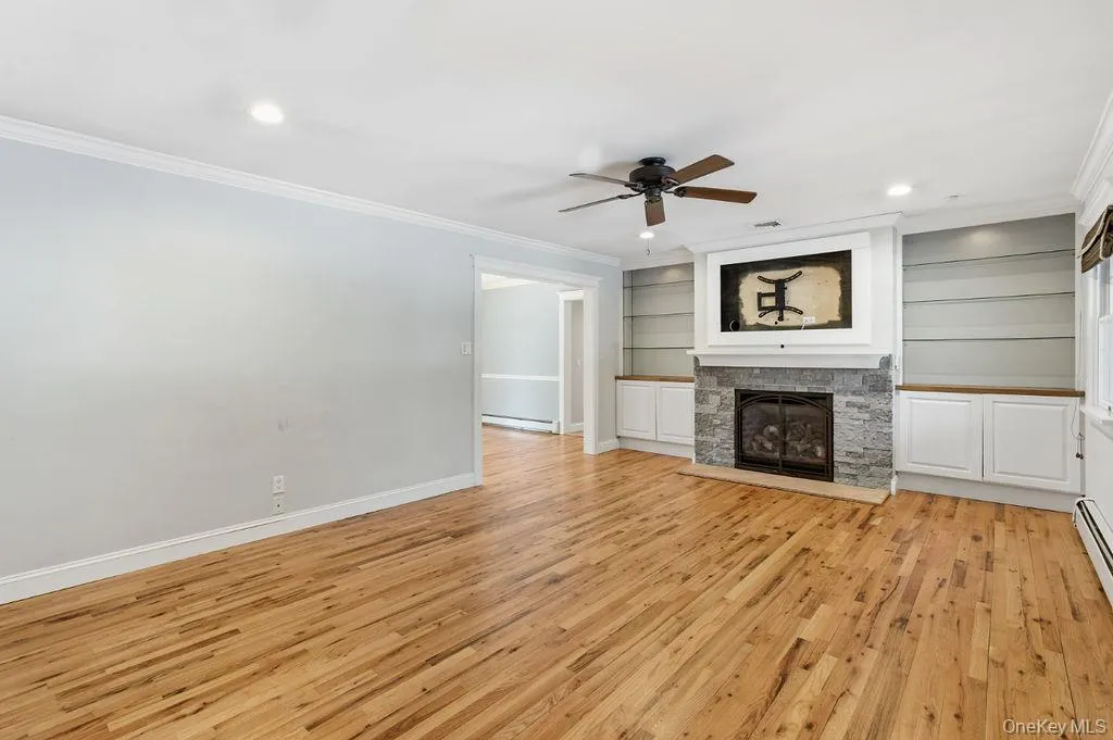 Hardwood flooring, recessed lighting, built-in cabinetry, stone-clad fireplace, and a ceiling fan Hardwood flooring, recessed lighting, built-in cabinetry, stone-clad fireplace, and a ceiling fan