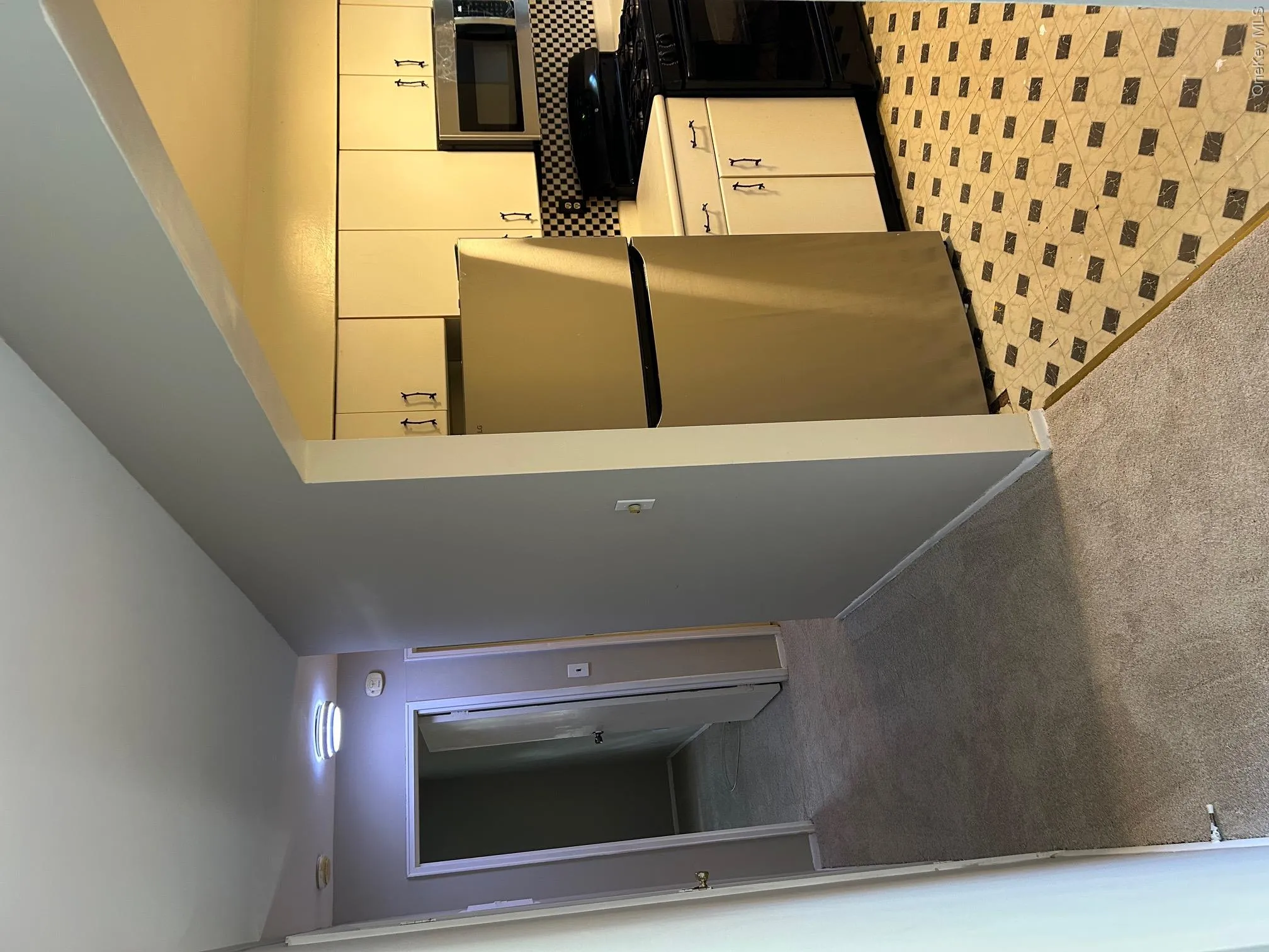 Kitchen with refrigerator, stove, light countertops, light carpet, and backsplash Kitchen with refrigerator, stove, light countertops, light carpet, and backsplash