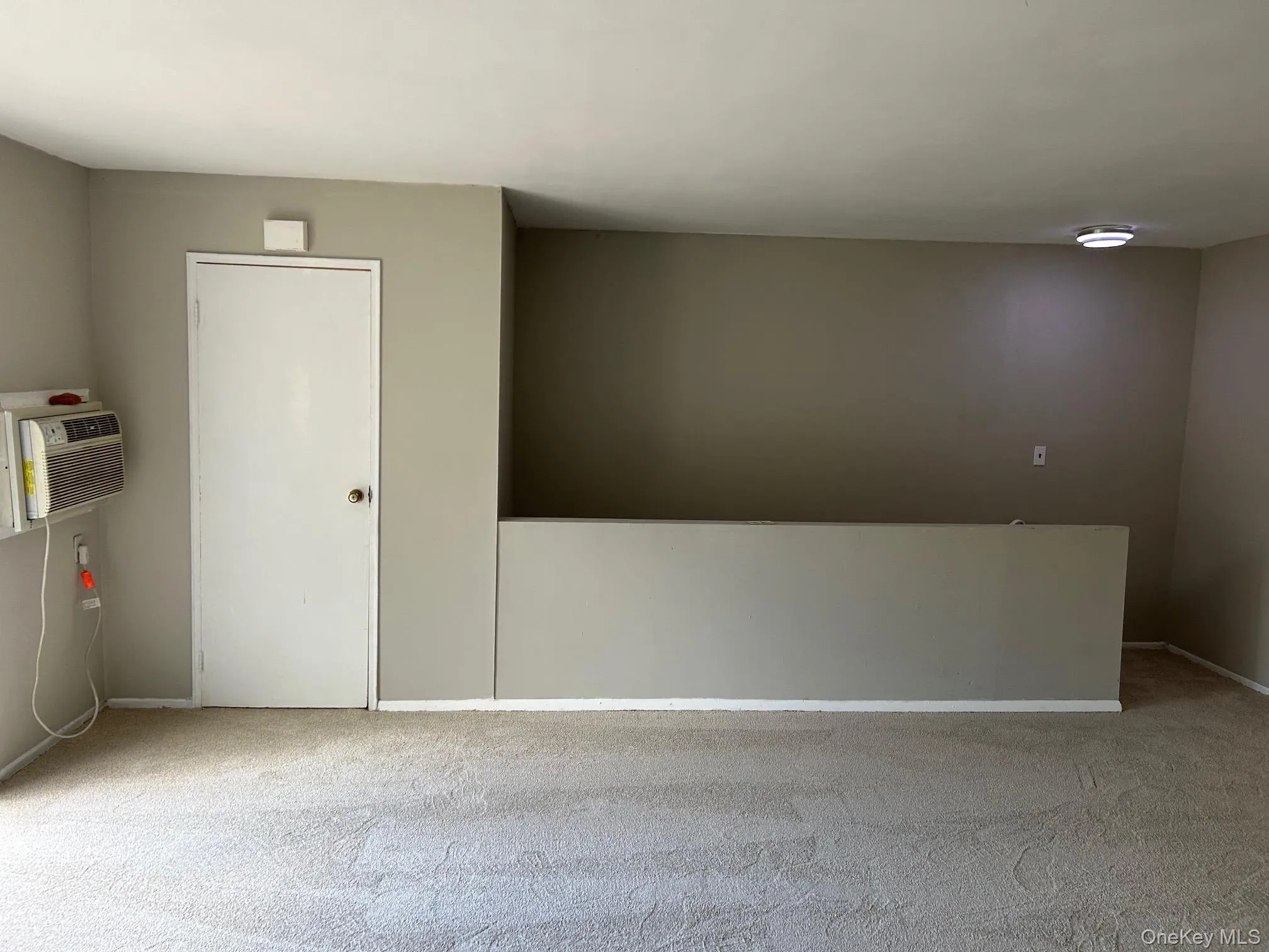 Empty room featuring light carpet and a wall mounted AC Empty room featuring light carpet and a wall mounted AC