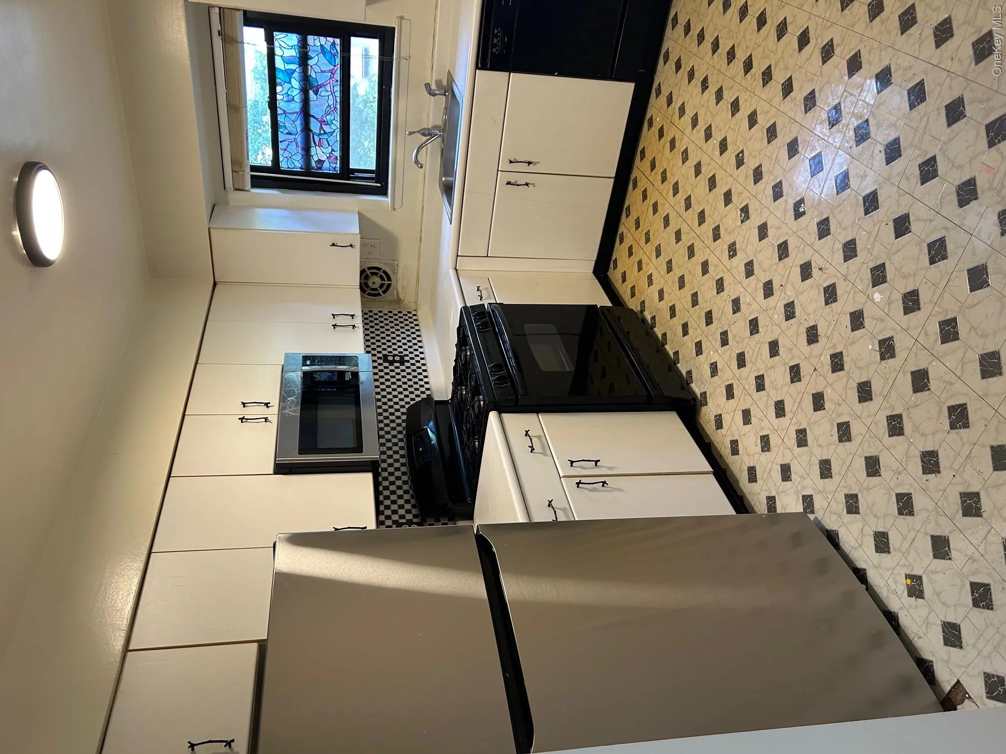 Kitchen featuring stainless steel fridge, light countertops, black gas range oven, and white microwave Kitchen featuring stainless steel fridge, light countertops, black gas range oven, and white microwave