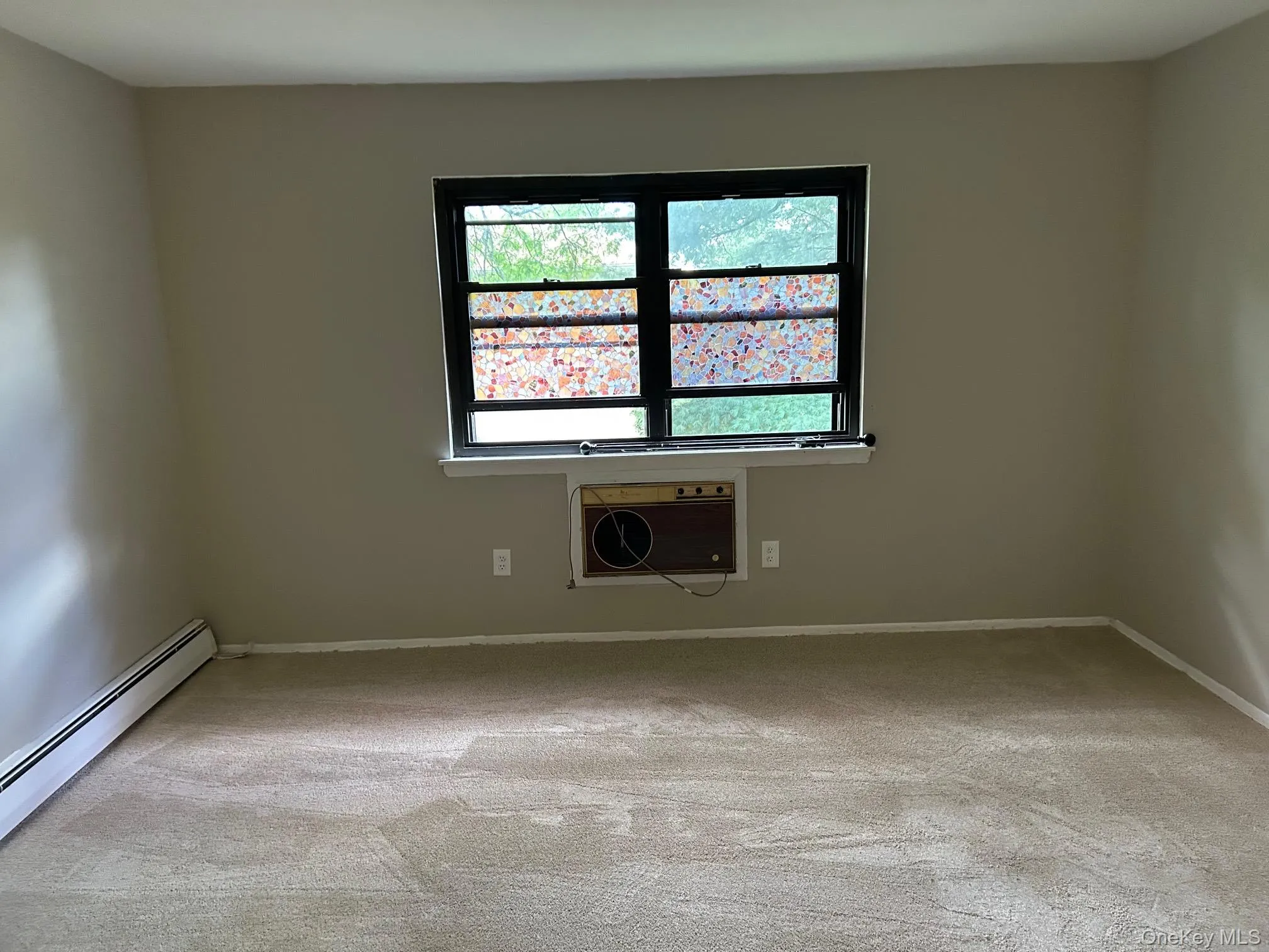 Spare room featuring light colored carpet, a baseboard radiator, and a wall unit AC Spare room featuring light colored carpet, a baseboard radiator, and a wall unit AC