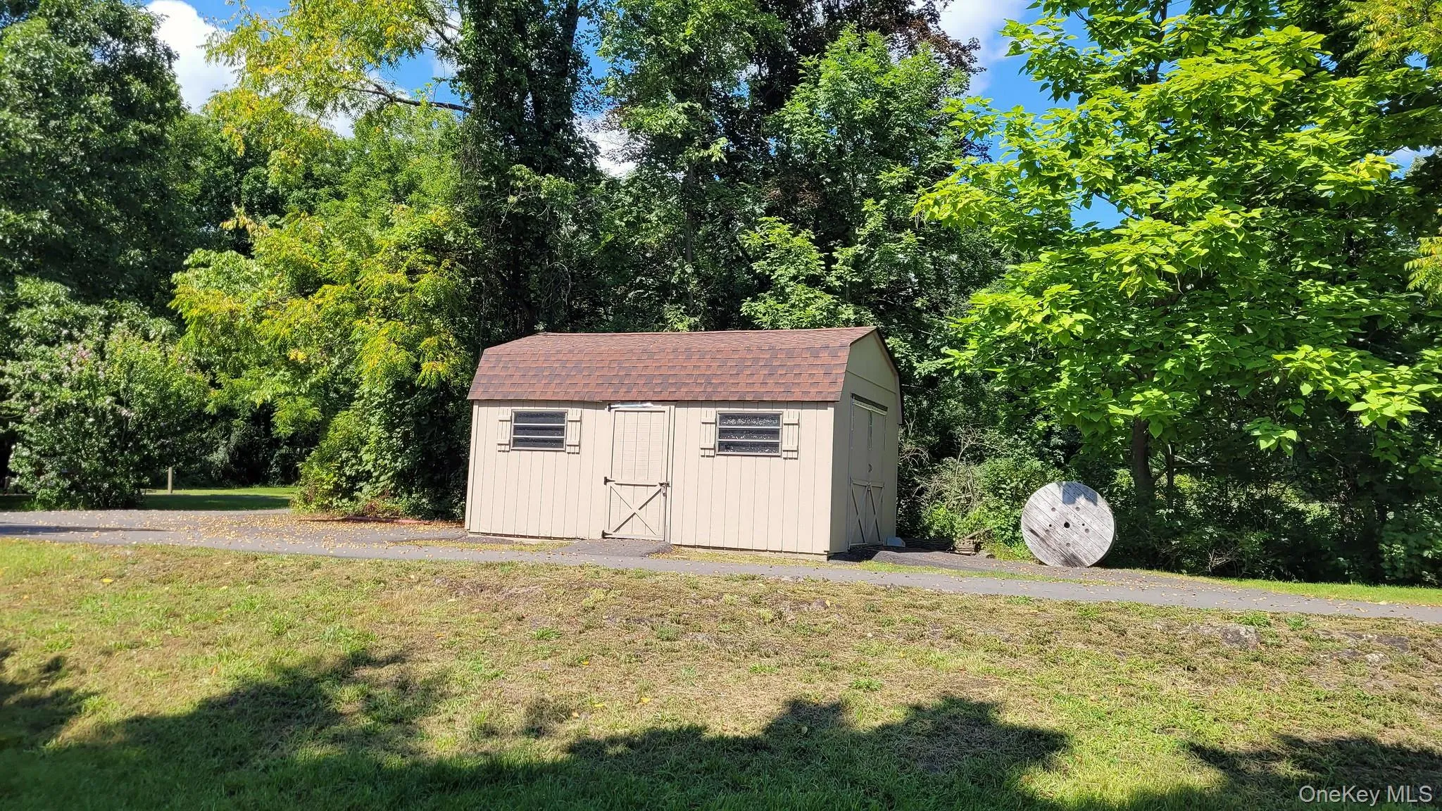 Storage shed with a brown shingle roof, two windows with shutters, and a double-door entry Storage shed with a brown shingle roof, two windows with shutters, and a double-door entry
