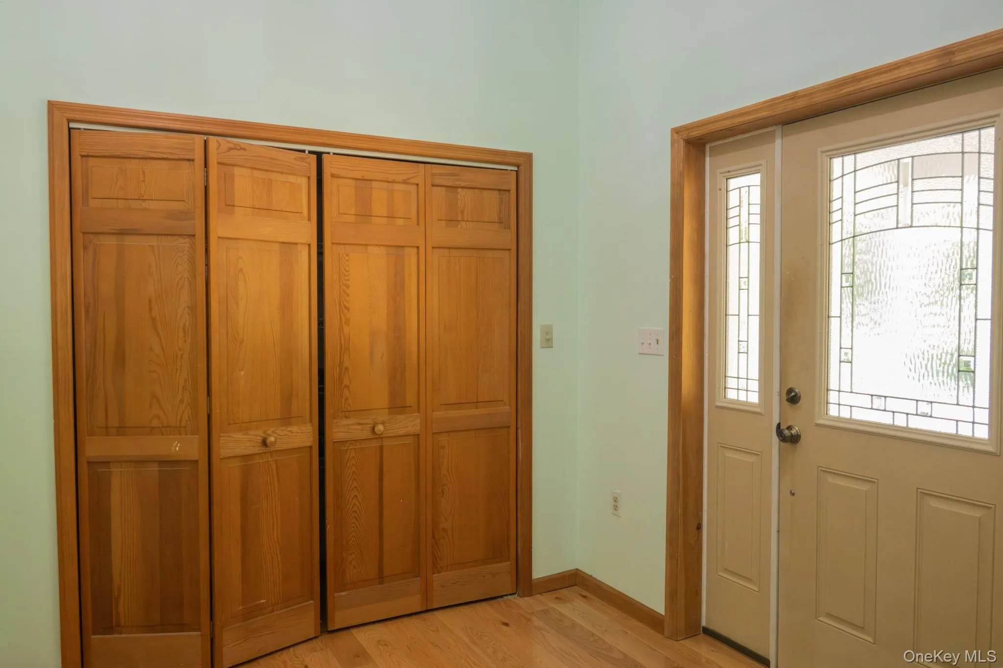 Entryway featuring wood-finish flooring, a bi-fold closet, and an entry door with decorative glass Entryway featuring wood-finish flooring, a bi-fold closet, and an entry door with decorative glass