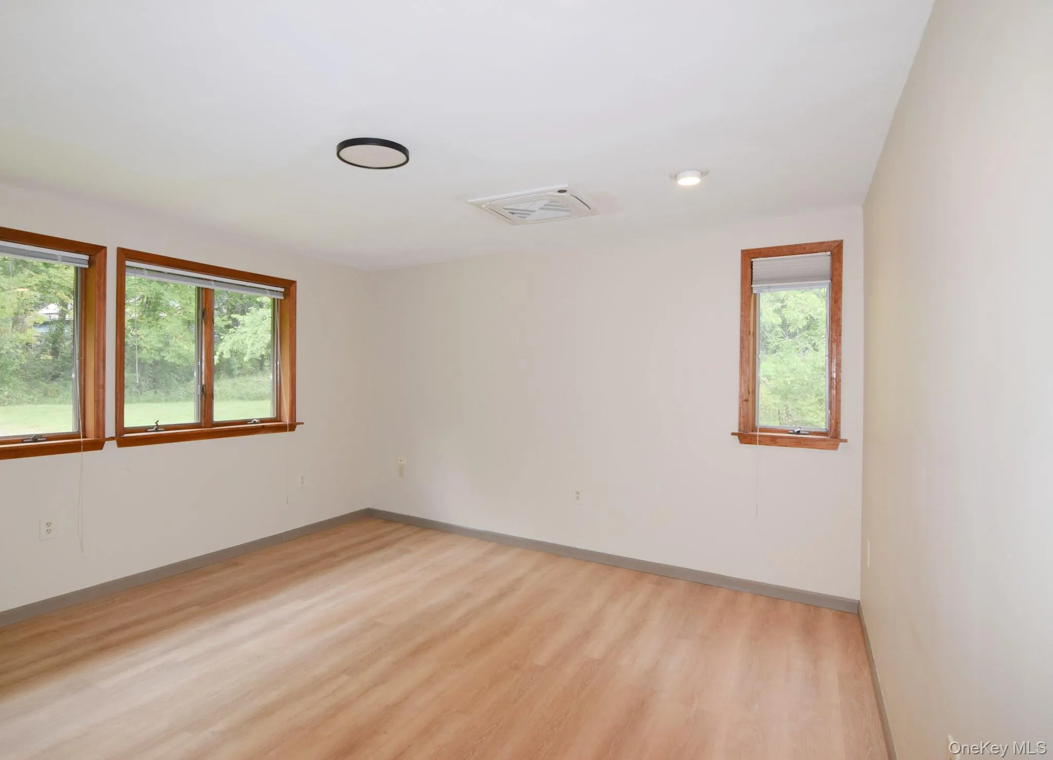 Light wood-finish flooring, white walls, and natural wood window frames. The large window faces the front. Light wood-finish flooring, white walls, and natural wood window frames. The large window faces the front.