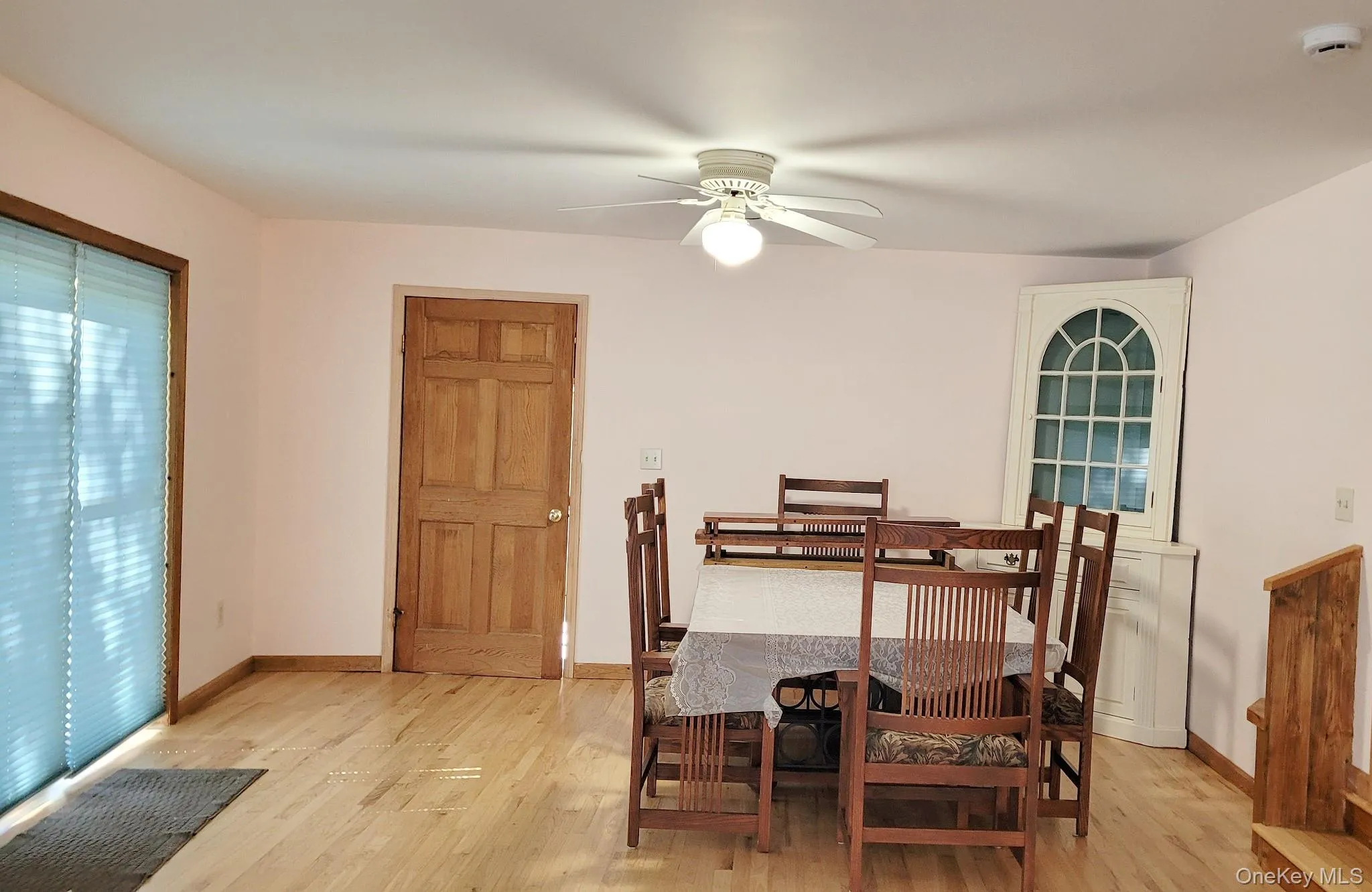 Light wood-finish flooring with a ceiling fan with integrated lighting and a paneled wood door Light wood-finish flooring with a ceiling fan with integrated lighting and a paneled wood door