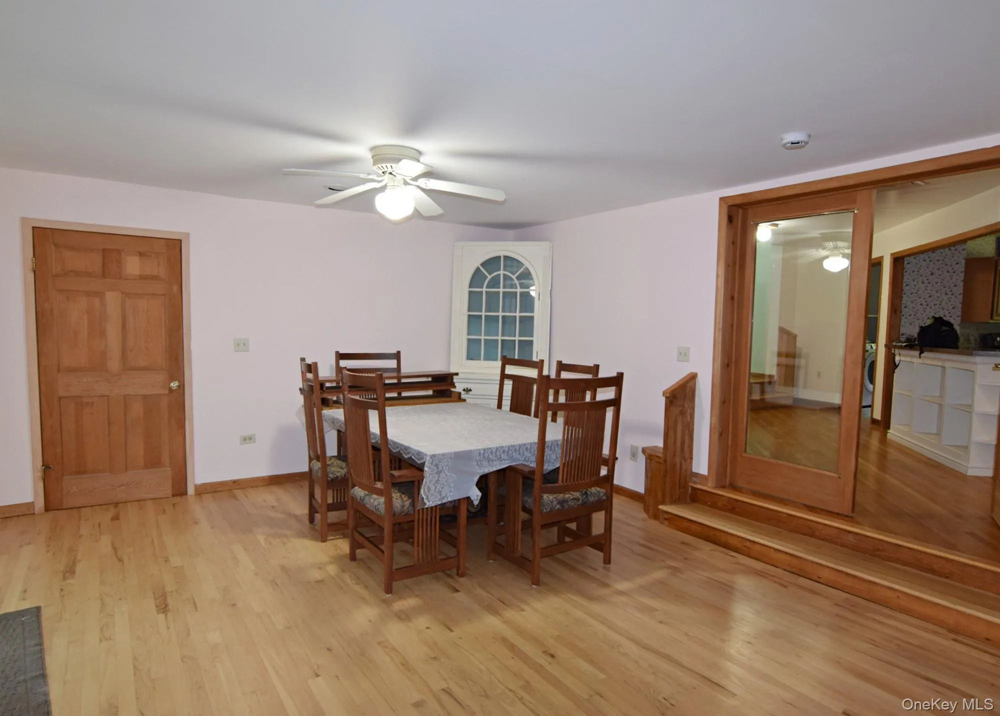 Hardwood flooring, paneled interior door, ceiling fan with light fixture, arched window, and wood-finish sliding door Hardwood flooring, paneled interior door, ceiling fan with light fixture, arched window, and wood-finish sliding door