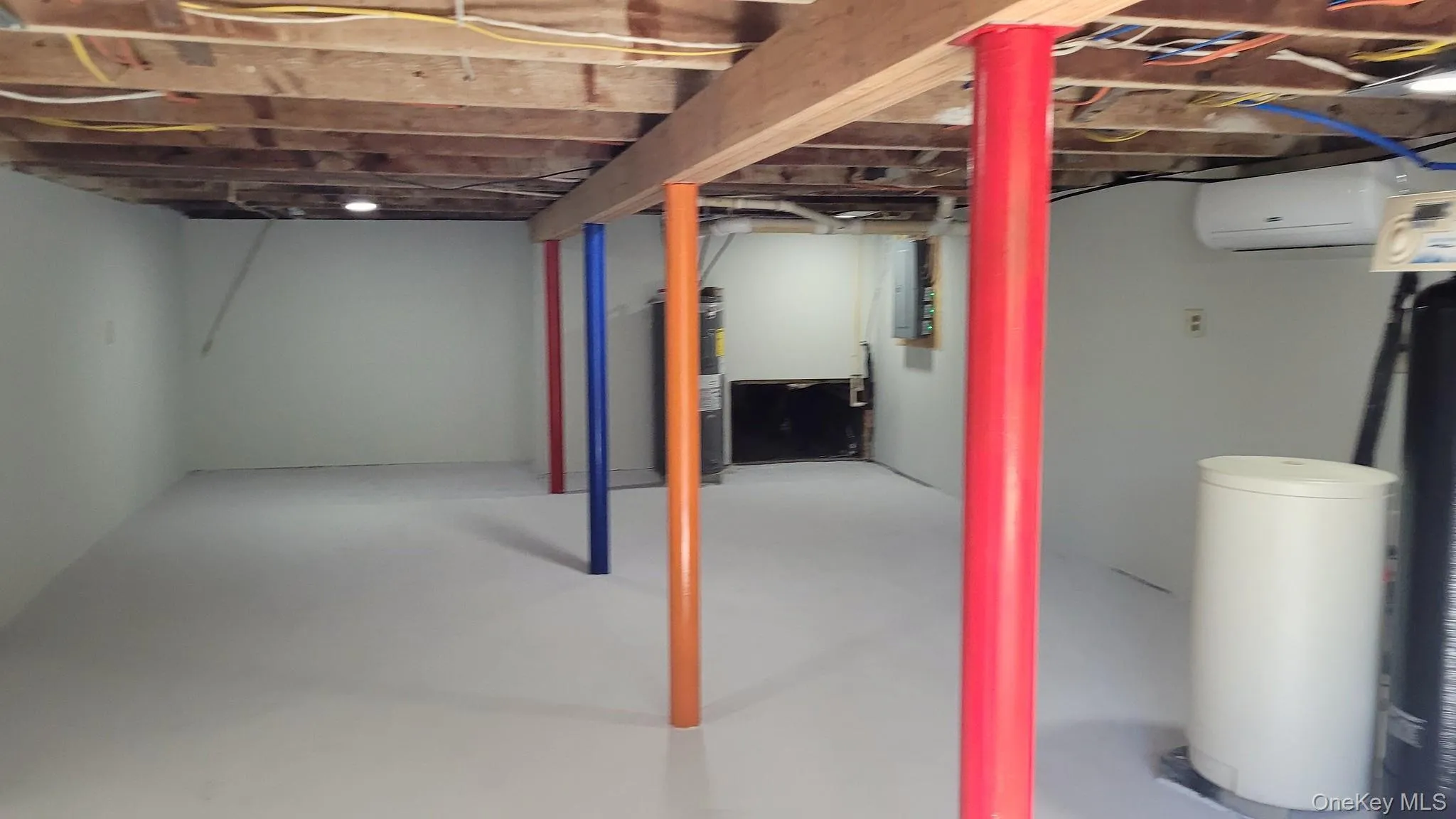 Unfinished lower level with exposed ceiling joists, painted support columns, and light gray walls.This area is directly below the converted barn. Unfinished lower level with exposed ceiling joists, painted support columns, and light gray walls.This area is directly below the converted barn.