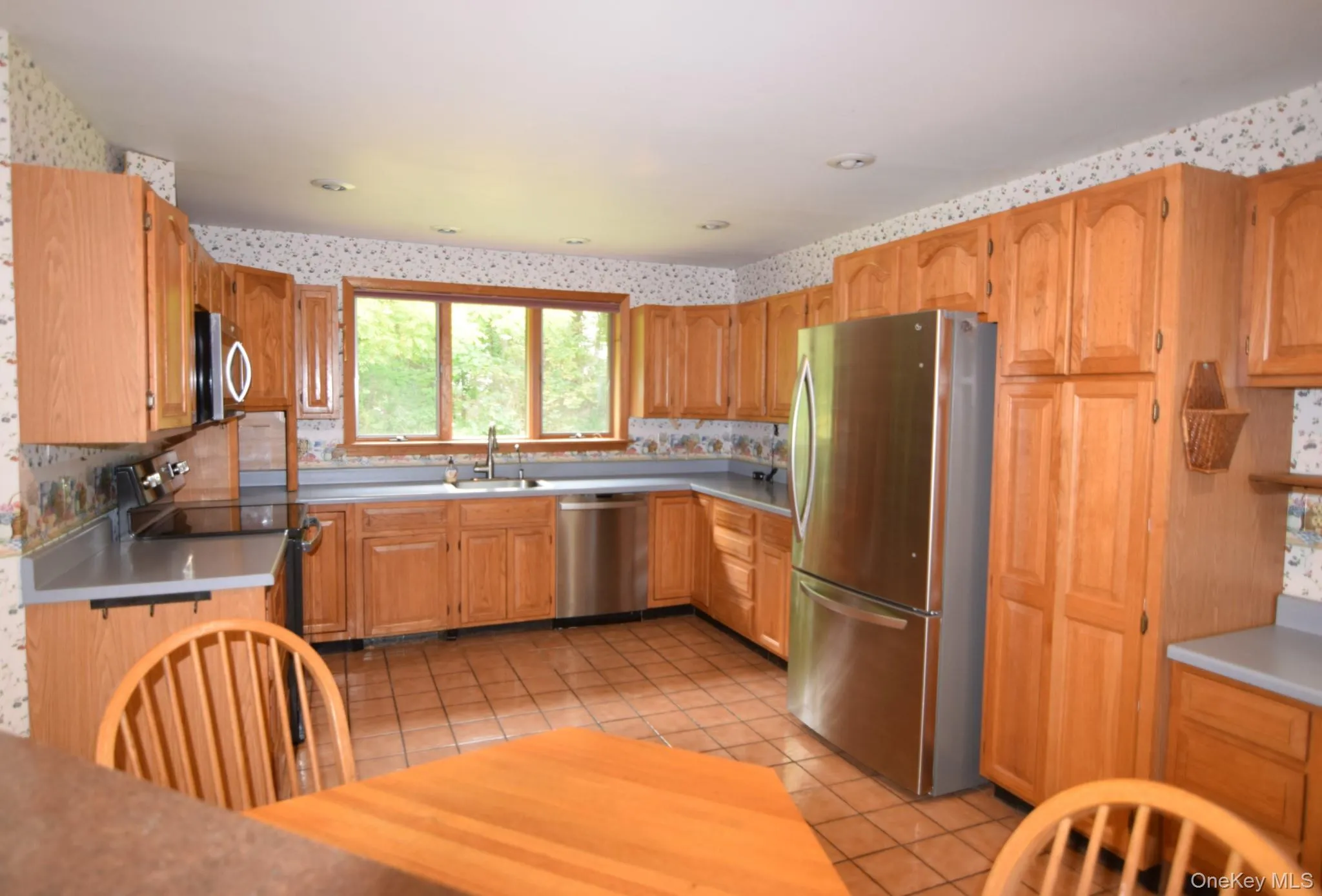 Wood-finish cabinetry, stainless steel appliances, recessed lighting, and tile flooring Wood-finish cabinetry, stainless steel appliances, recessed lighting, and tile flooring
