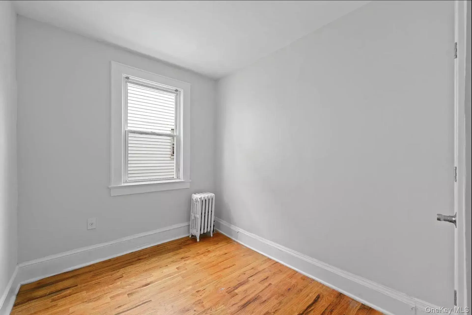 Unfurnished room featuring radiator heating unit, baseboards, and light wood-type flooring Unfurnished room featuring radiator heating unit, baseboards, and light wood-type flooring