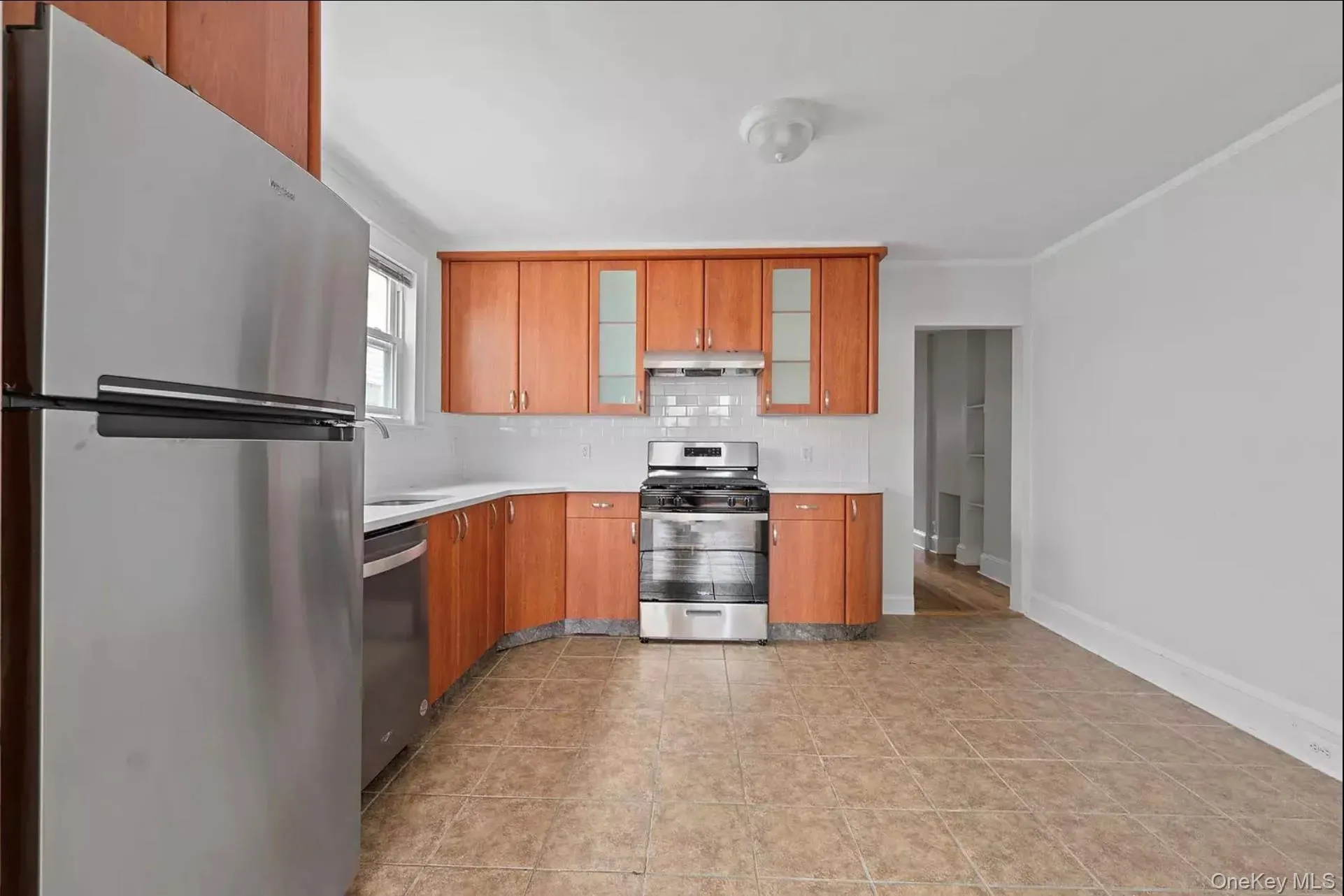 Kitchen with stainless steel appliances, under cabinet range hood, light countertops, tasteful backsplash, and a sink Kitchen with stainless steel appliances, under cabinet range hood, light countertops, tasteful backsplash, and a sink