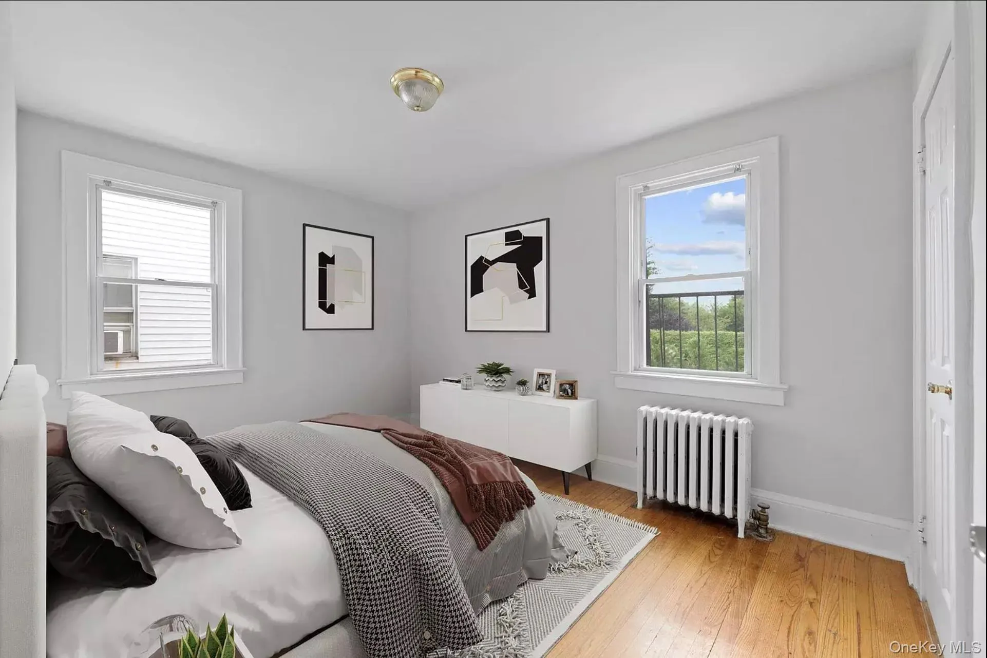 Bedroom featuring radiator, light wood finished floors, and baseboards Bedroom featuring radiator, light wood finished floors, and baseboards