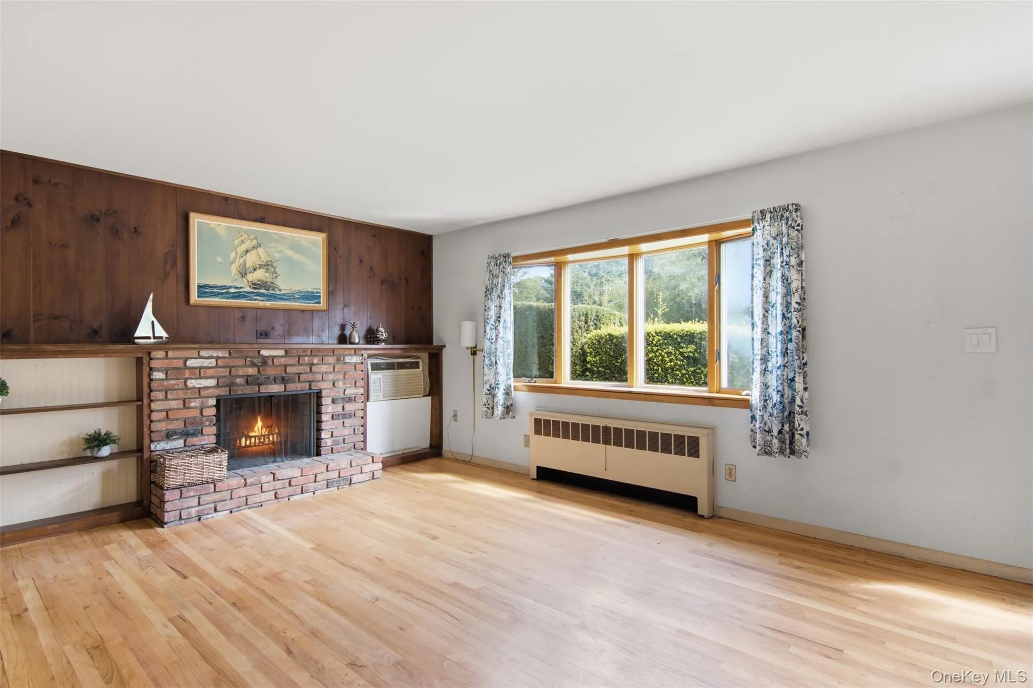 Living room with beautiful hardwood floors, wood burning fireplace and Anderson bay window. Living room with beautiful hardwood floors, wood burning fireplace and Anderson bay window.