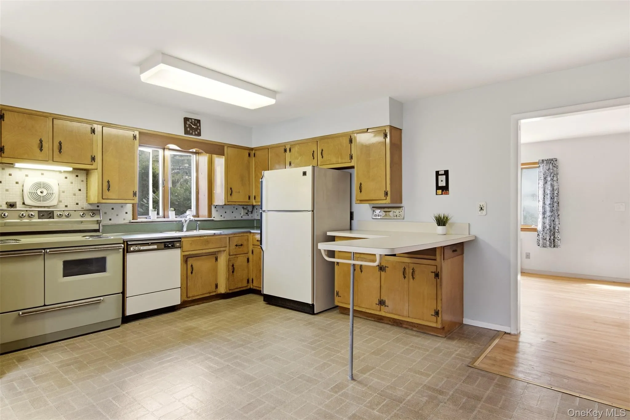 Kitchen with electric stove wood cabinets and breakfast bar. (Dishwasher AS-IS) Kitchen with electric stove wood cabinets and breakfast bar. (Dishwasher AS-IS)