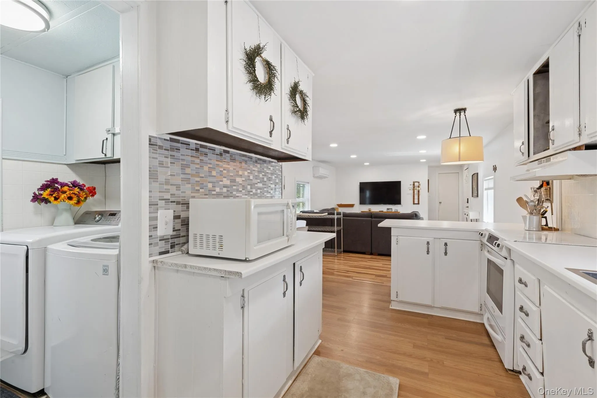 Kitchen featuring decorative backsplash, decorative light fixtures, white cabinets, light countertops, and recessed lighting Kitchen featuring decorative backsplash, decorative light fixtures, white cabinets, light countertops, and recessed lighting