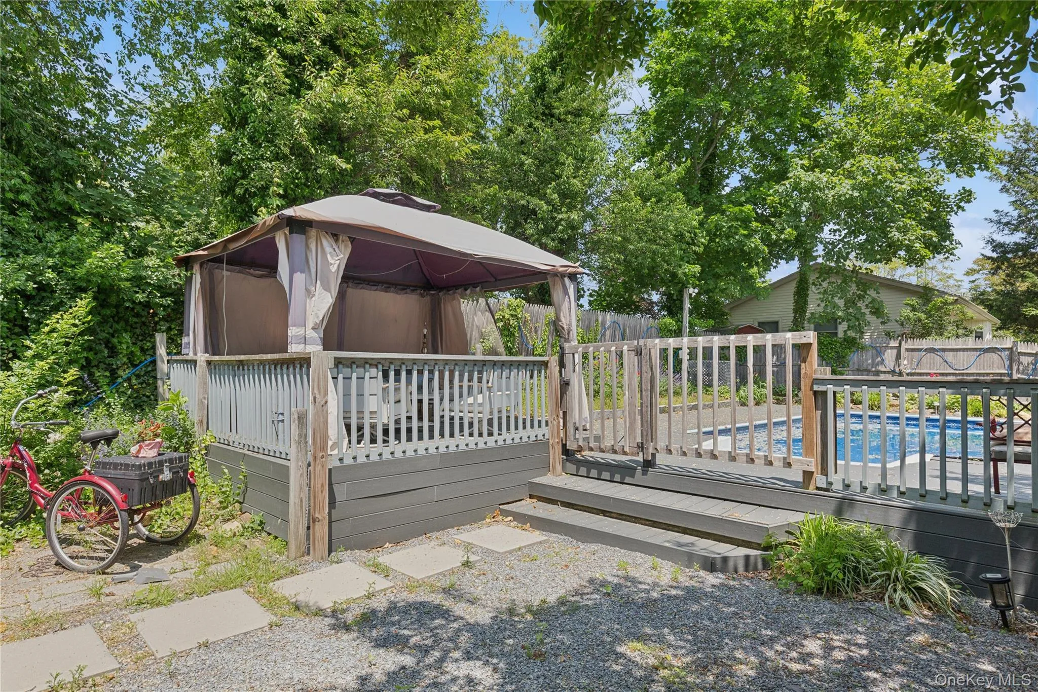 Wooden terrace featuring a gazebo and a fenced backyard Wooden terrace featuring a gazebo and a fenced backyard