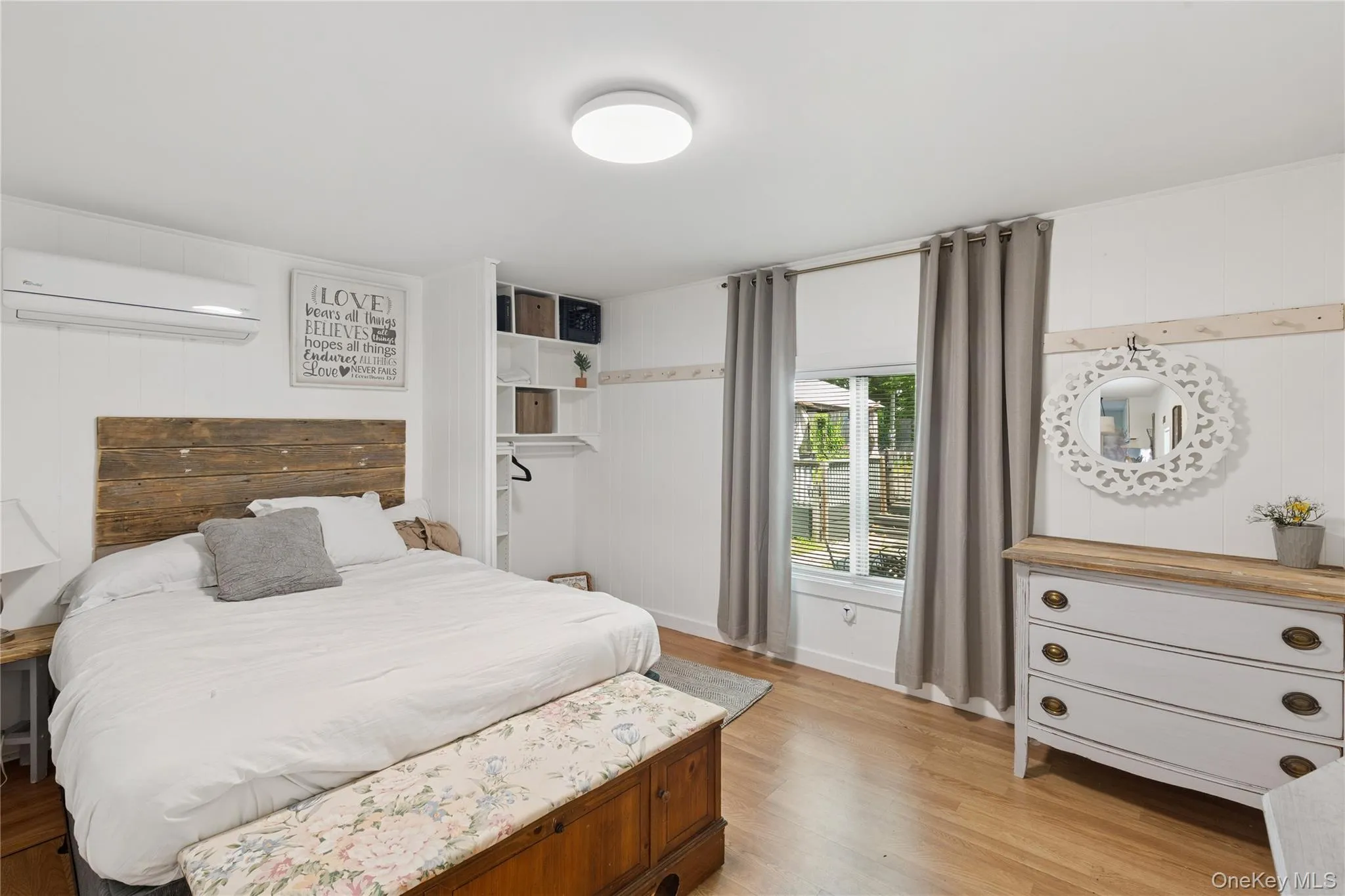 Bedroom featuring light wood-style flooring, wood walls, and a wall mounted air conditioner Bedroom featuring light wood-style flooring, wood walls, and a wall mounted air conditioner