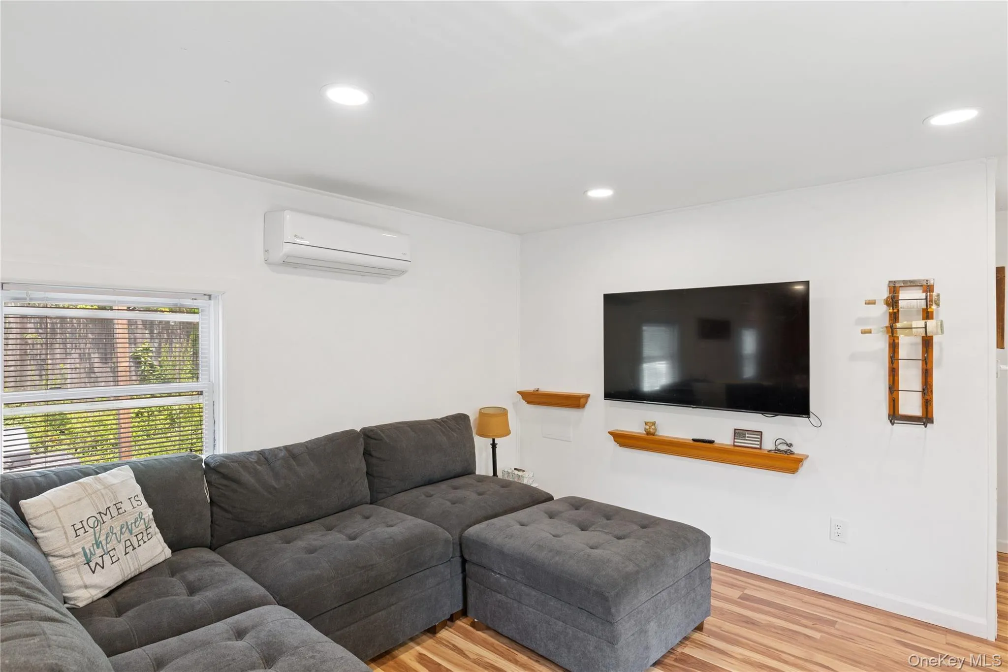 Living area with light wood-style flooring, recessed lighting, and a wall mounted air conditioner Living area with light wood-style flooring, recessed lighting, and a wall mounted air conditioner