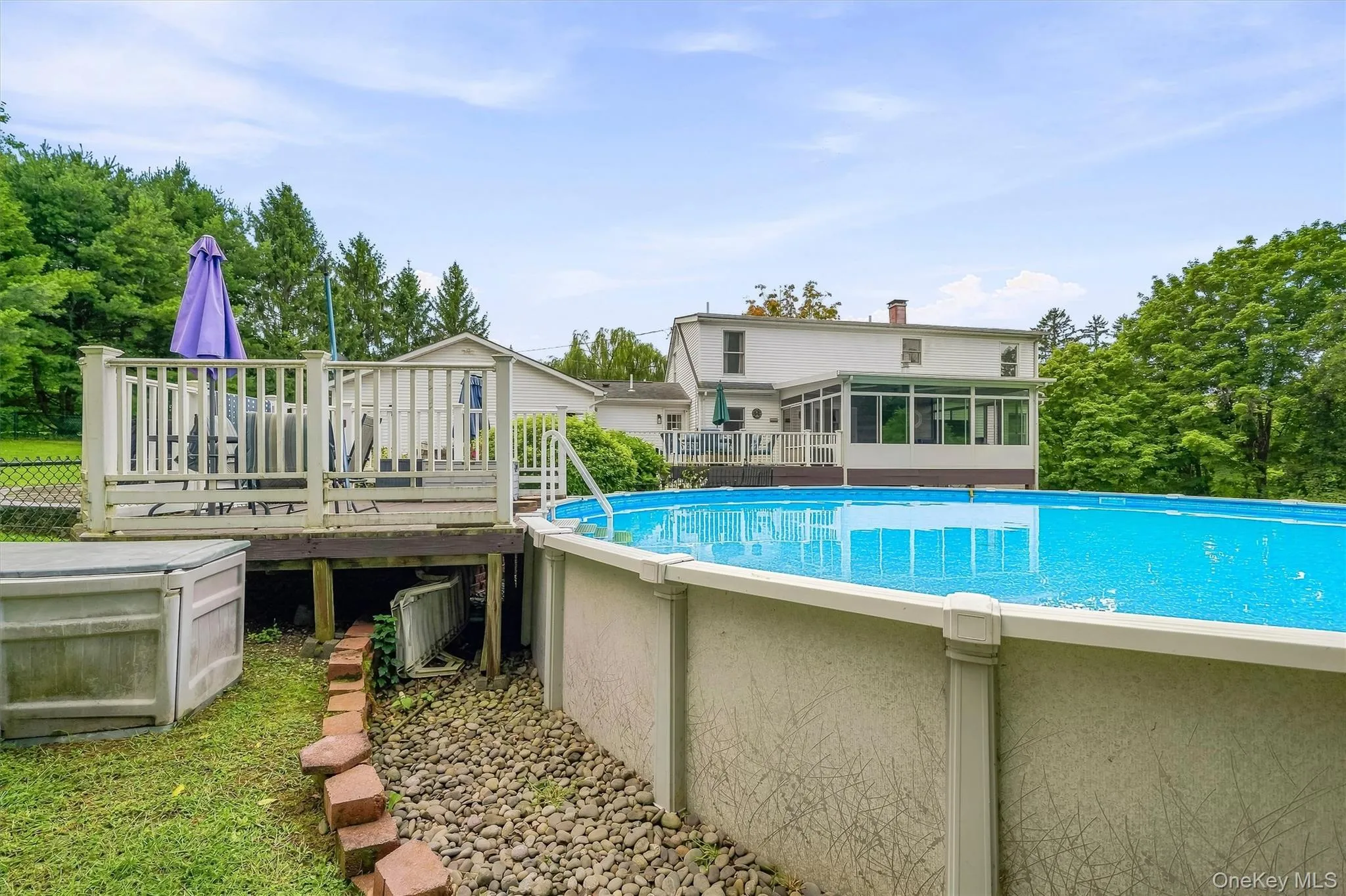 Above-ground swimming pool, elevated deck, sunroom, and mature trees Above-ground swimming pool, elevated deck, sunroom, and mature trees