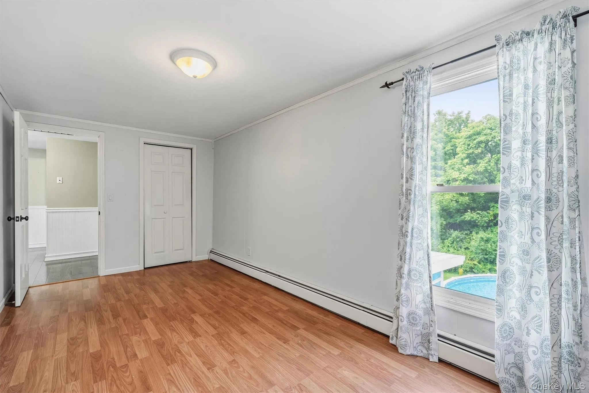 Wood-finish flooring, white walls, and a window with natural light Wood-finish flooring, white walls, and a window with natural light