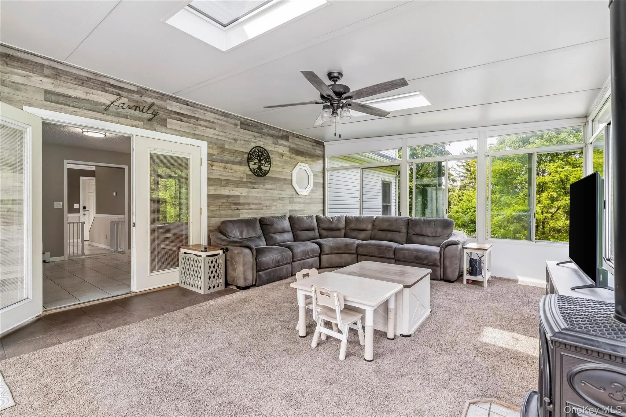 Sunroom with two skylights, a ceiling fan, wood-plank accent wall, and glass-paneled French doors Sunroom with two skylights, a ceiling fan, wood-plank accent wall, and glass-paneled French doors