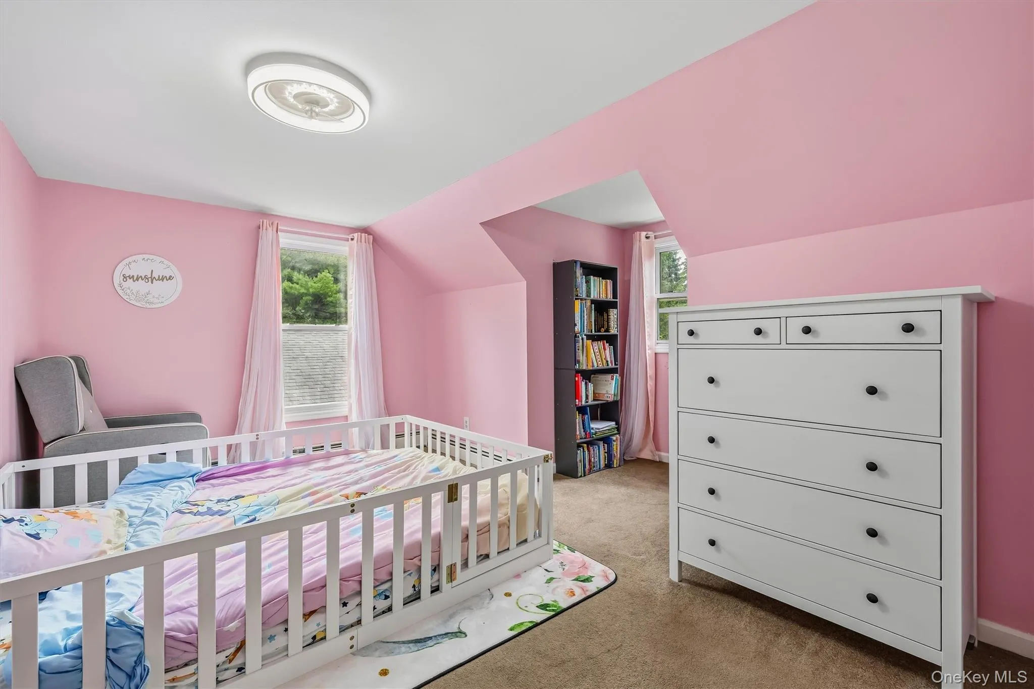 Ceiling-mounted light fixture, dual windows with white window treatments, and sloped ceiling details Ceiling-mounted light fixture, dual windows with white window treatments, and sloped ceiling details
