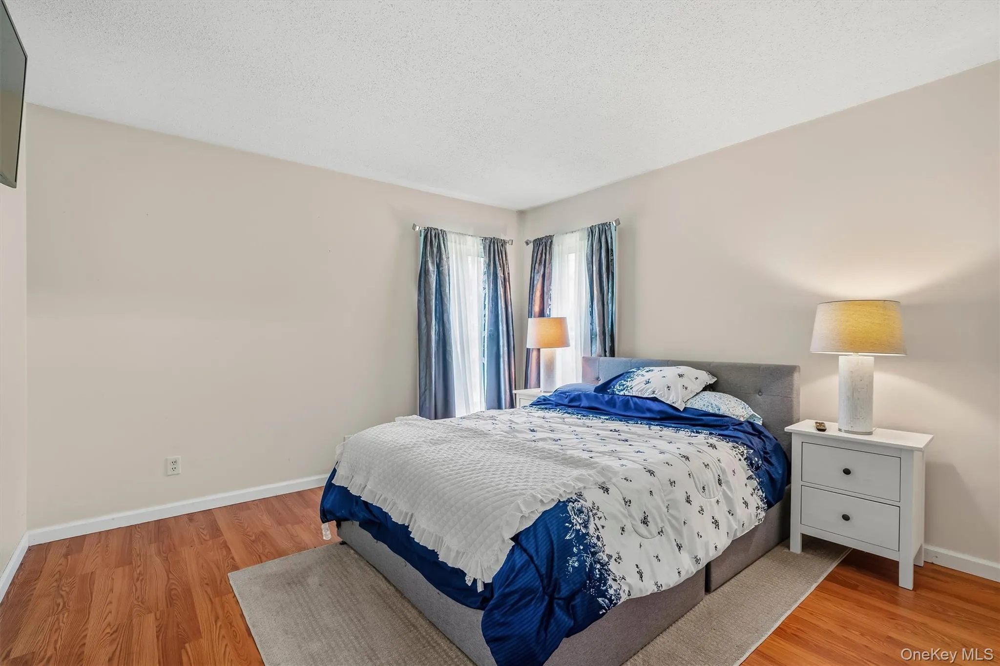 Spacious bedroom with hardwood flooring and plenty of natural light. Spacious bedroom with hardwood flooring and plenty of natural light.