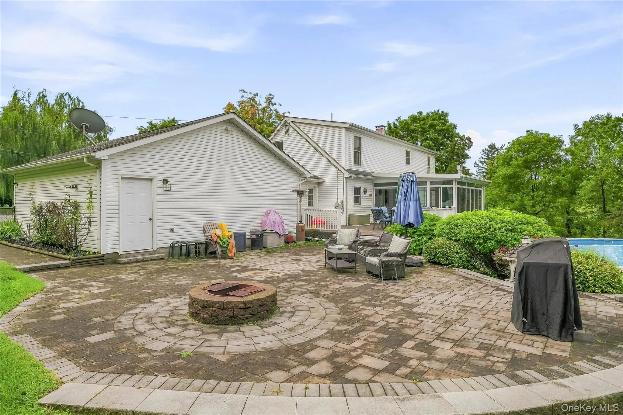 Large paver patio with built-in fire pit, seating area, and access to the pool and deck. Large paver patio with built-in fire pit, seating area, and access to the pool and deck.