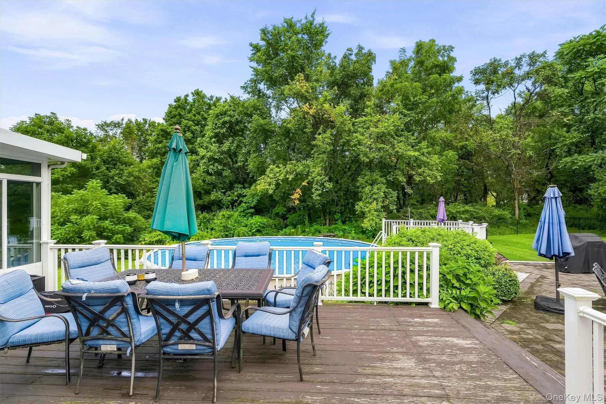 Outdoor deck overlooking the above-ground pool and tree-lined backyard. Outdoor deck overlooking the above-ground pool and tree-lined backyard.