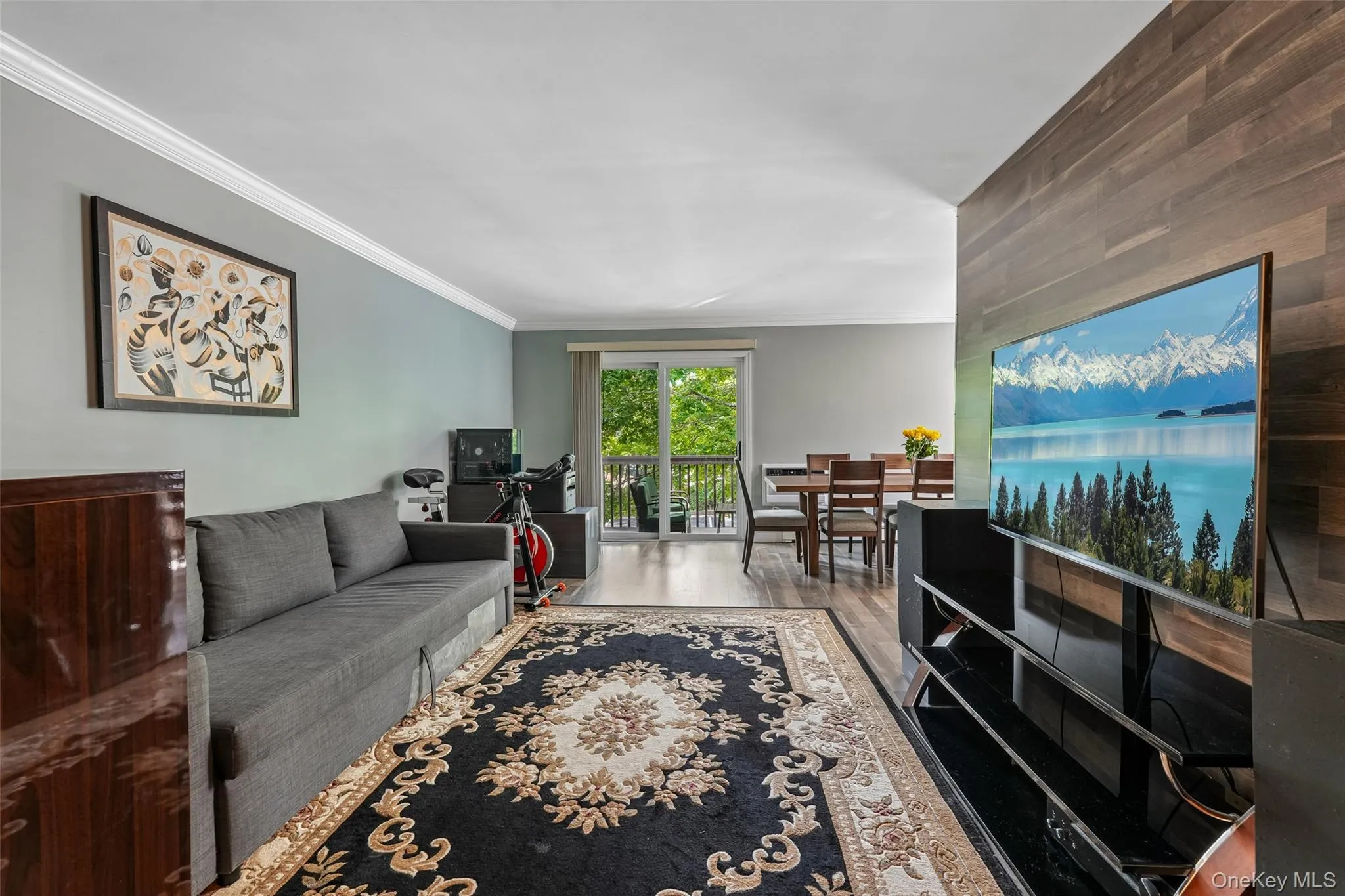 Interior living space featuring wood-finish flooring, crown molding, and a wood-paneled accent wall Interior living space featuring wood-finish flooring, crown molding, and a wood-paneled accent wall