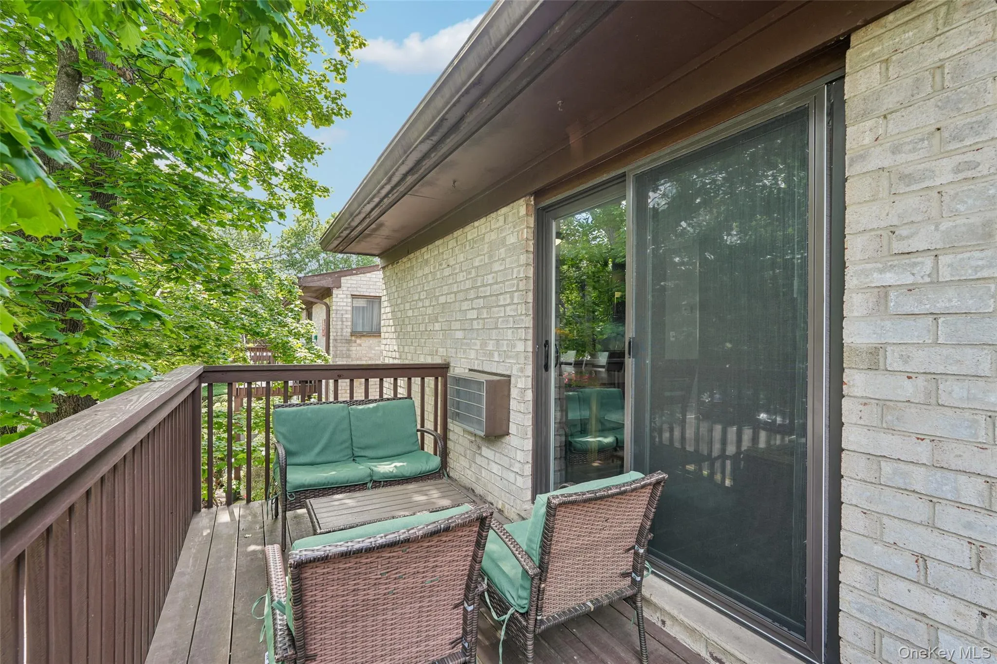 Wood-finish deck with a wood railing and a brick-finish exterior Wood-finish deck with a wood railing and a brick-finish exterior