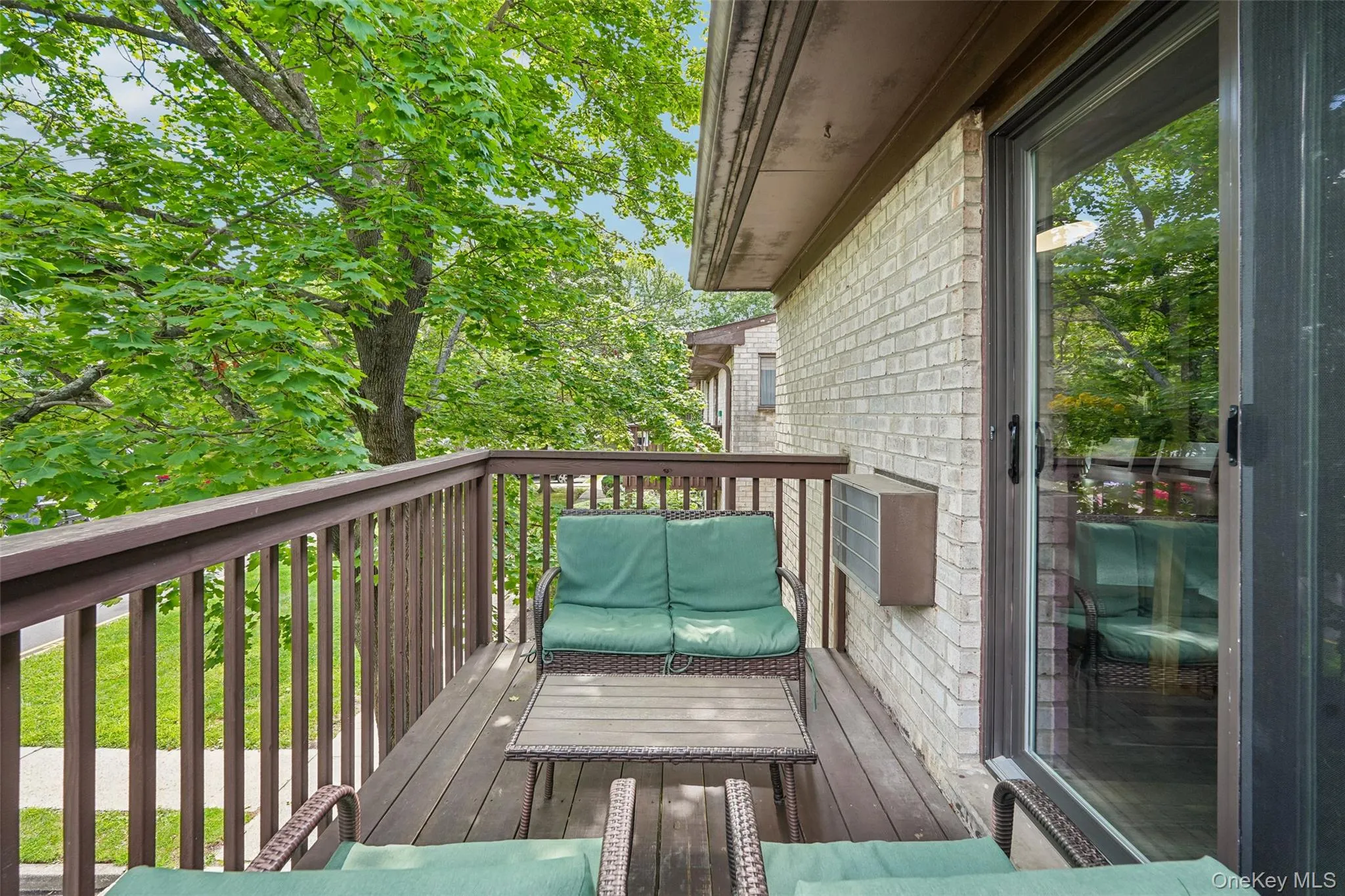 Private balcony featuring a wood-finish deck, vertical slat railing, and a sliding glass door Private balcony featuring a wood-finish deck, vertical slat railing, and a sliding glass door