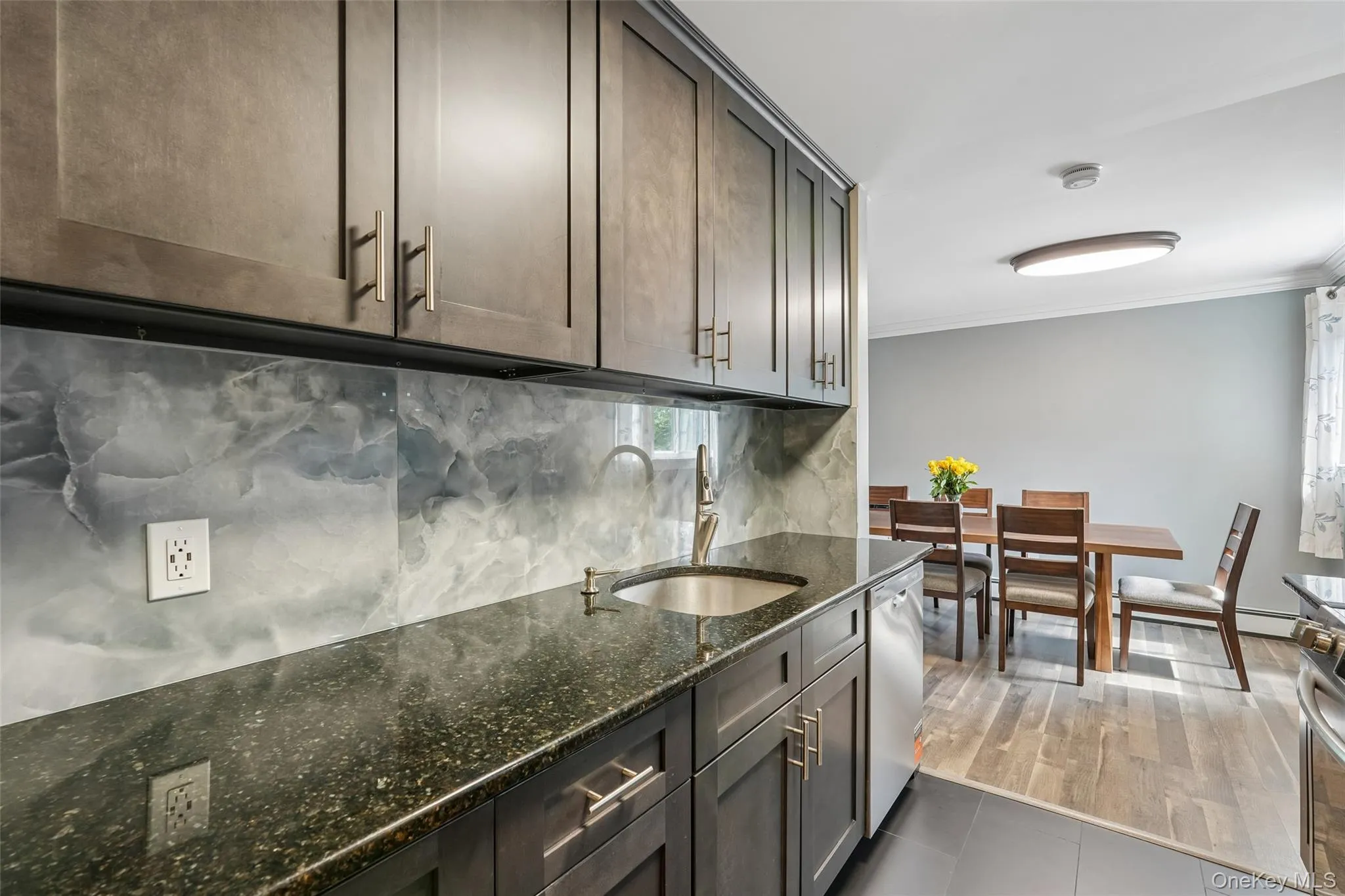 Kitchen featuring dark wood-finish cabinetry, a dark speckled countertop, and a stainless steel undermount sink Kitchen featuring dark wood-finish cabinetry, a dark speckled countertop, and a stainless steel undermount sink