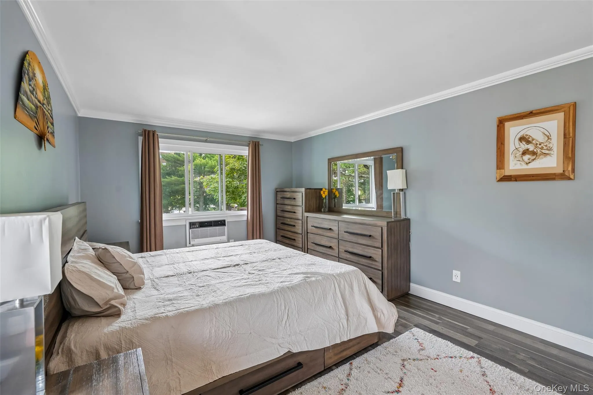 Window with exterior views, crown molding, wood-finish flooring, and light blue wall color Window with exterior views, crown molding, wood-finish flooring, and light blue wall color