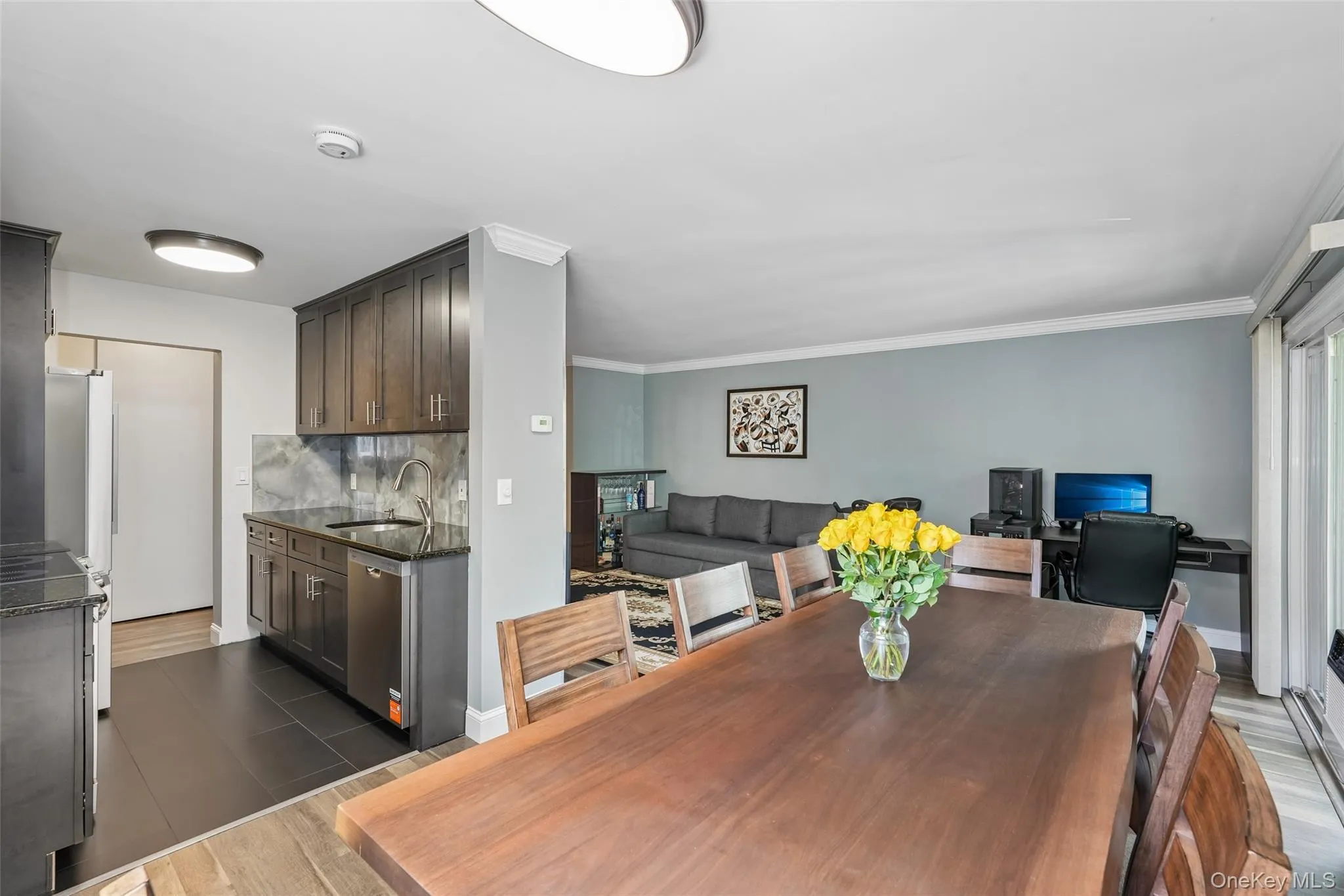 Kitchenette with dark wood-finish cabinetry, dark countertops, and tile backsplash Kitchenette with dark wood-finish cabinetry, dark countertops, and tile backsplash