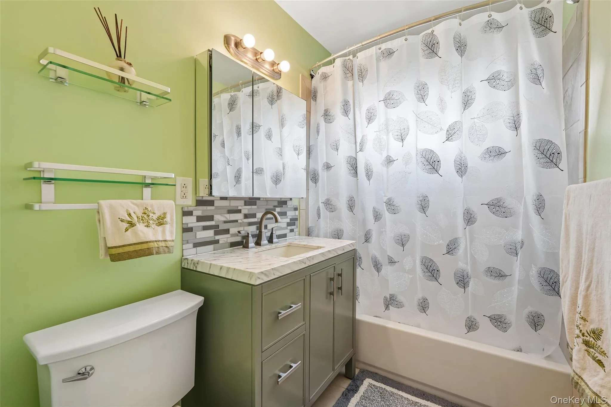 Vanity with a solid surface countertop, mosaic tile backsplash, and brushed nickel fixtures Vanity with a solid surface countertop, mosaic tile backsplash, and brushed nickel fixtures