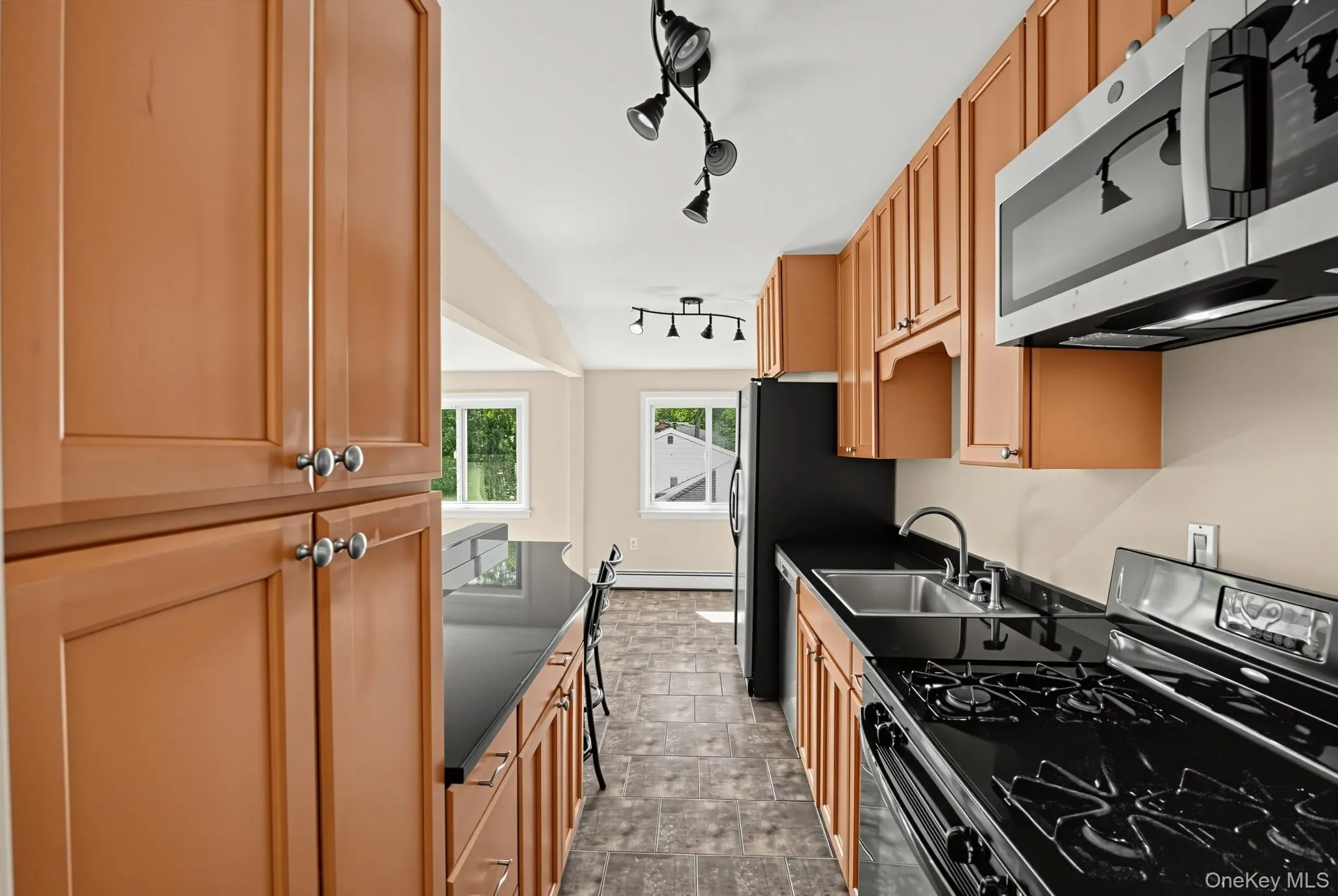 The galley kitchen offers abundant cabinetry and counter space, with natural light at the far end, plus a new stainless steel microwave and dishwasher. The galley kitchen offers abundant cabinetry and counter space, with natural light at the far end, plus a new stainless steel microwave and dishwasher.
